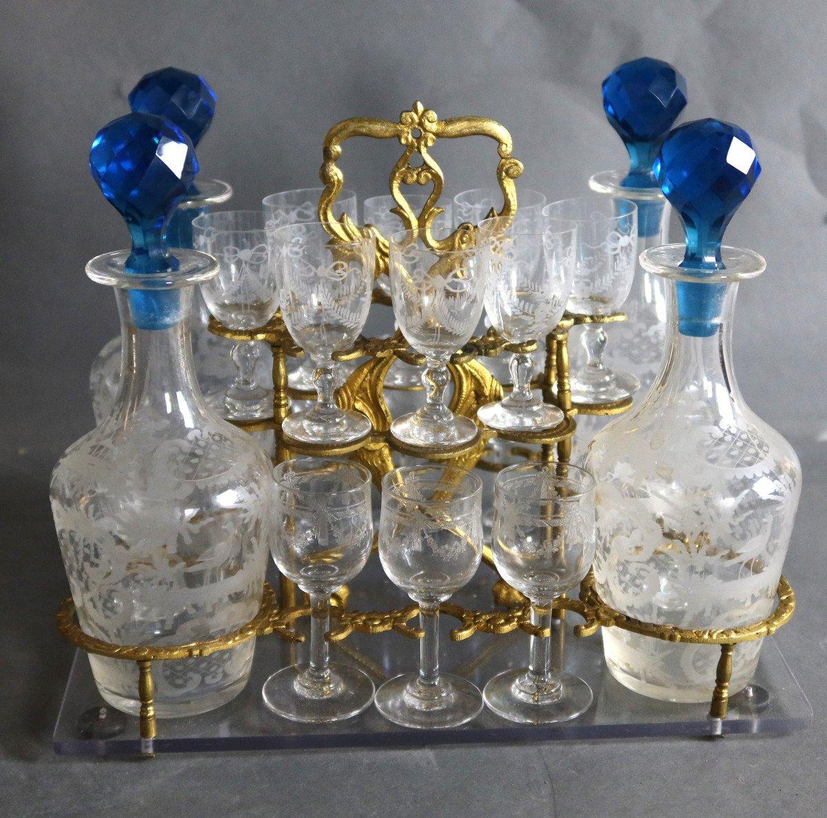 Liquor cellar in bronze and glass from the Napoleon III period. 
This cellar includes four carafes fitted with blue stoppers and sixteen engraved glasses (a few different glasses). 
This cellar is monogrammed 