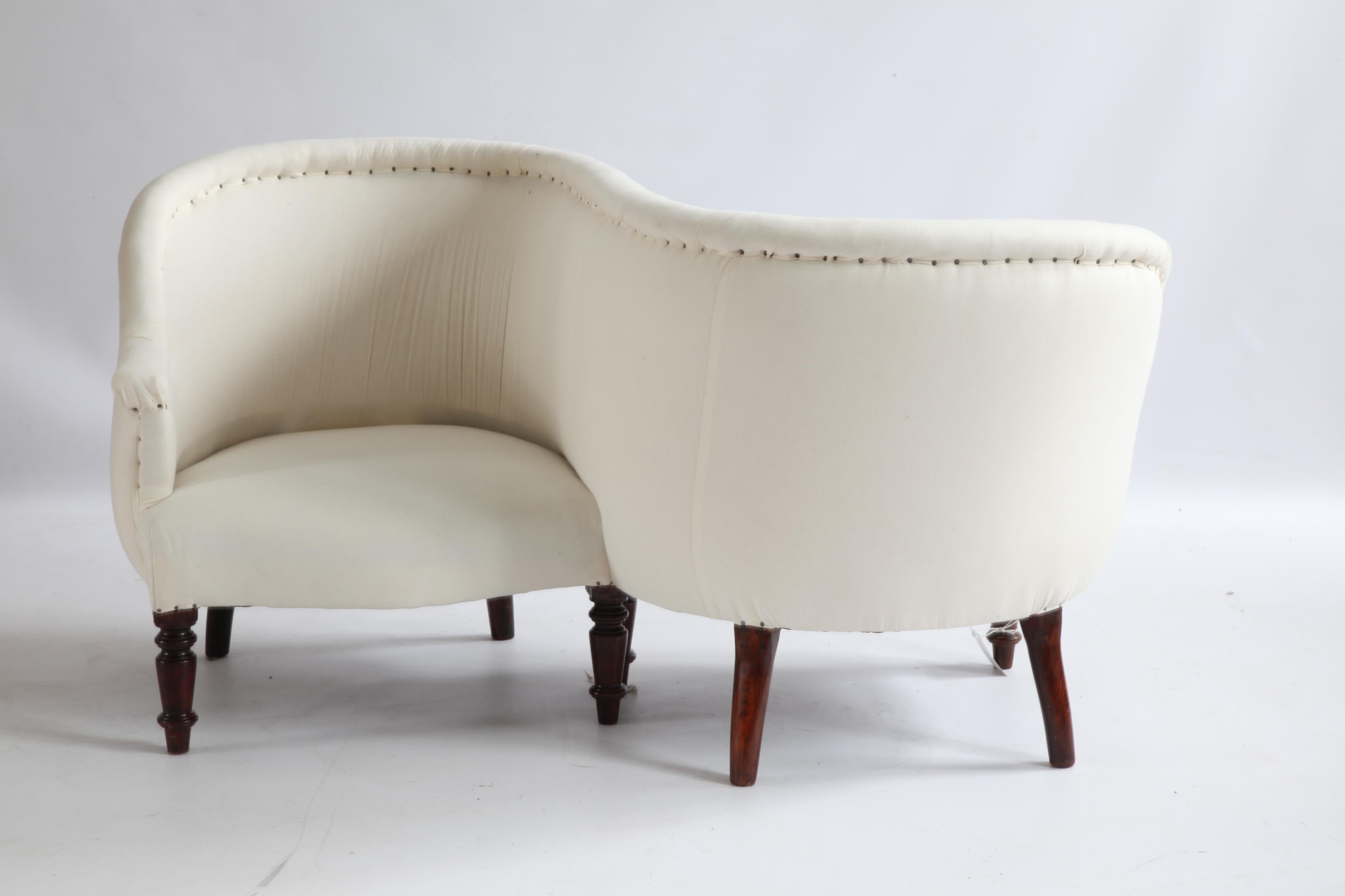 A Napoleon III period French confident also known as a conversation or love seat. Designed as an all upholstered fluid S curve frame with mahogany legs. The piece is upholstered in an ecru calico.