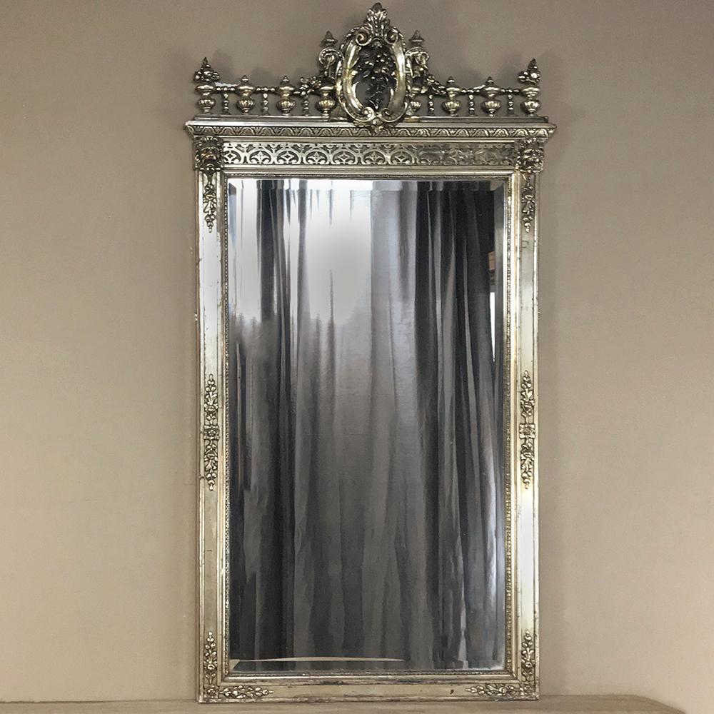 Napoleon III period French silver gilt mirror boasts amazing detail with the heraldic crest centered on the crown flanked by a colonnade and finials, with lions' heads and foliate sprays in relief on the lower frame, all enhanced by the silver gilt