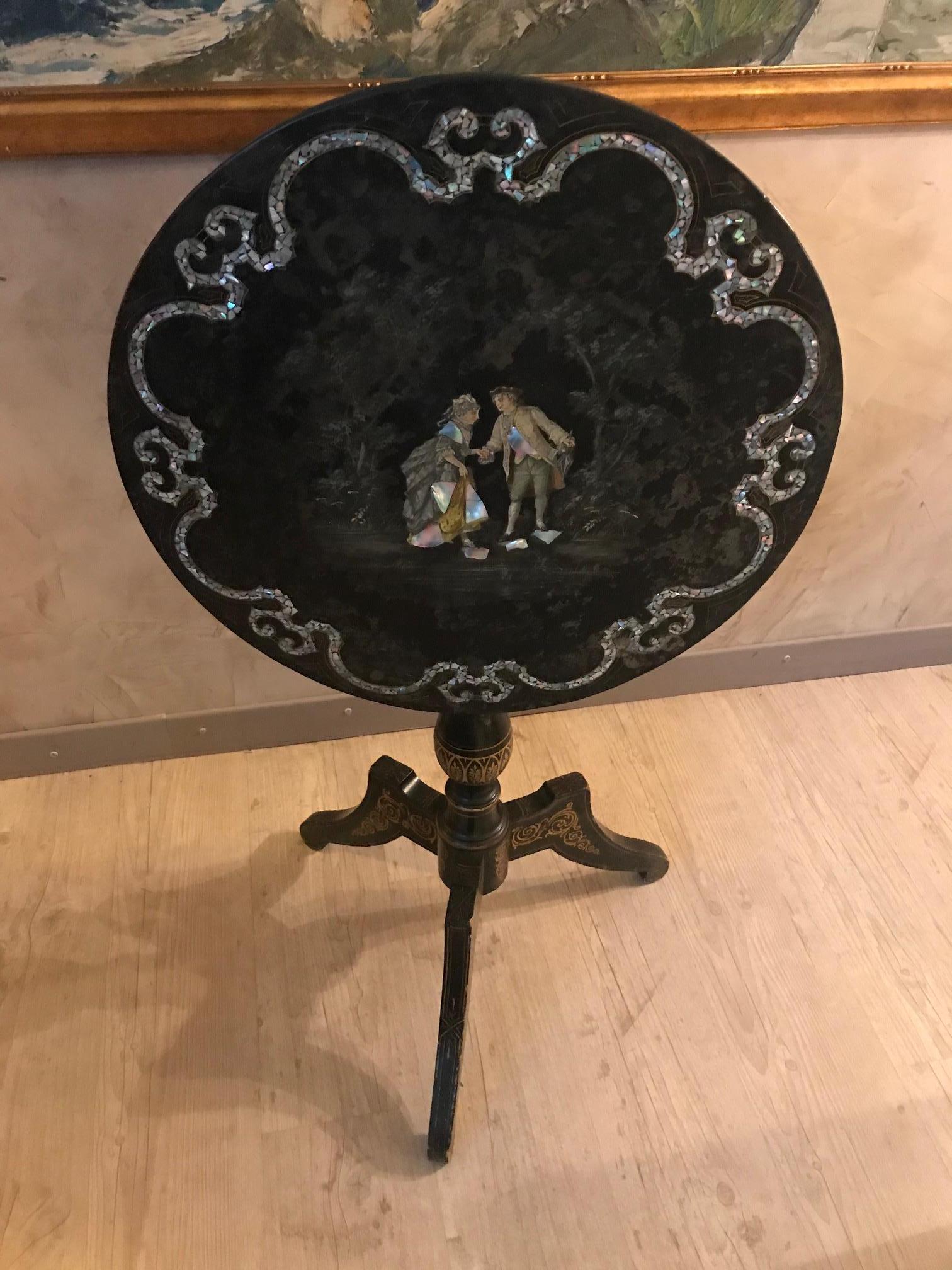 Very nice Napoleon III period Blackened pearwood and mother of pearl inlay foldin Gueridon from the 1870s. 
The base has a nice gilt marquetry and the top is made with mother of pearl inlay and we can see on the center a couple with also
