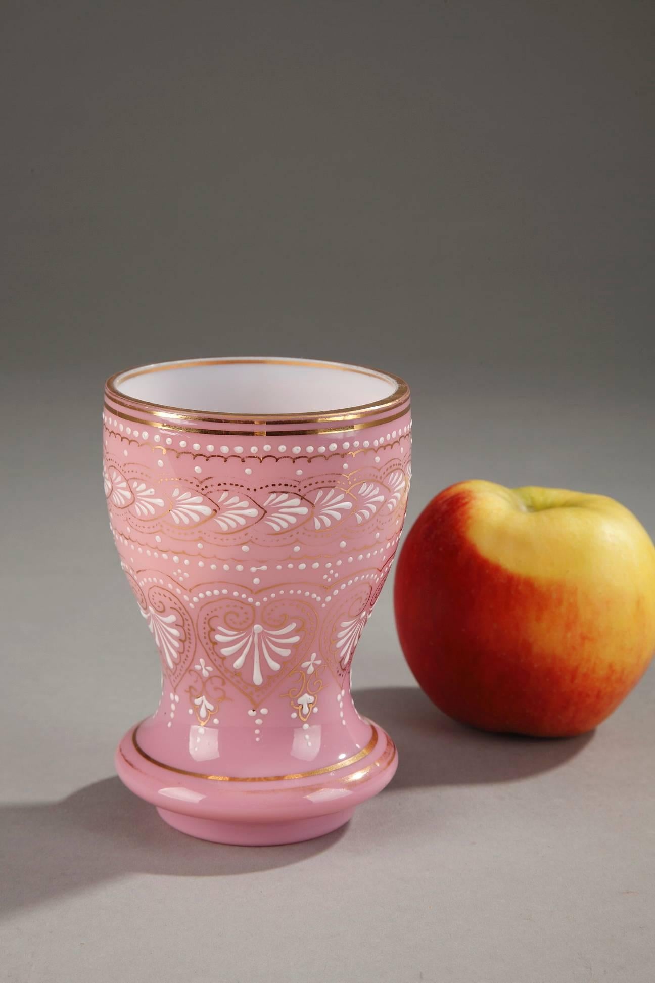 19th century cup crafted in pink opaline glass, embellished with palmettes, small pearls, and foliate motifs in white enamel. Thin bands of gold highlight the enamel as well as the base and rim of the cup. The precise and detailed enamel work