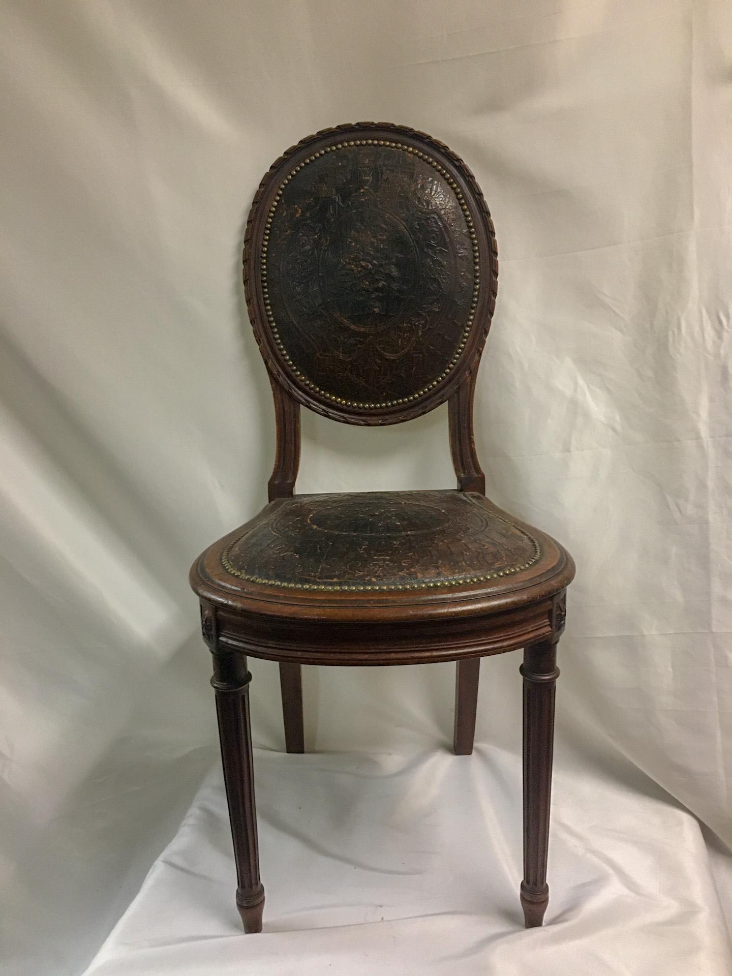 This handsome set of four petite Napoleon III French oak chairs feature embossed leather backs and seats framed in a myriad of brass tacks. The worn  leather adds to the charm of this sturdy and very detailed set. The leather pattern is of a basket