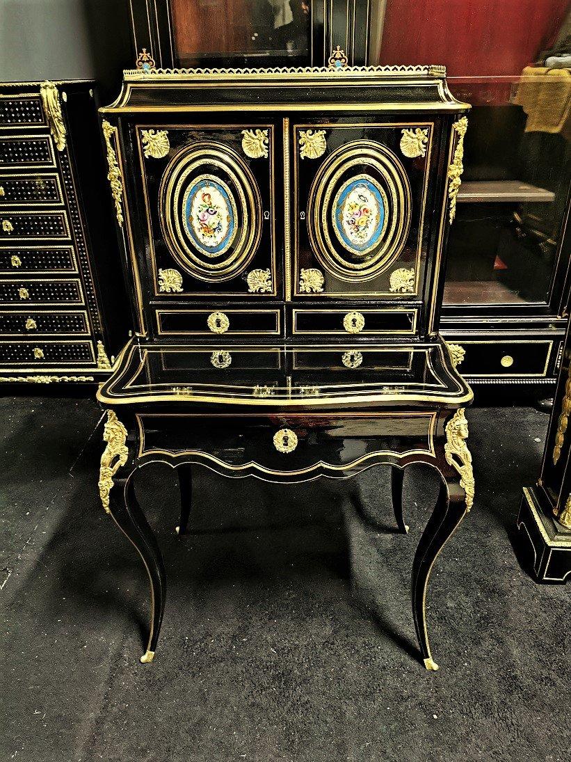 Napoleon III secretary in blackened fruitwood, Boulle marquetry style with brass nets, with two beautiful Sèvres porcelain plaques on the doors. Beautiful ornamentation of golden bronzes with spandrels, ingot molds, scraps, masks, gallery. Mahogany