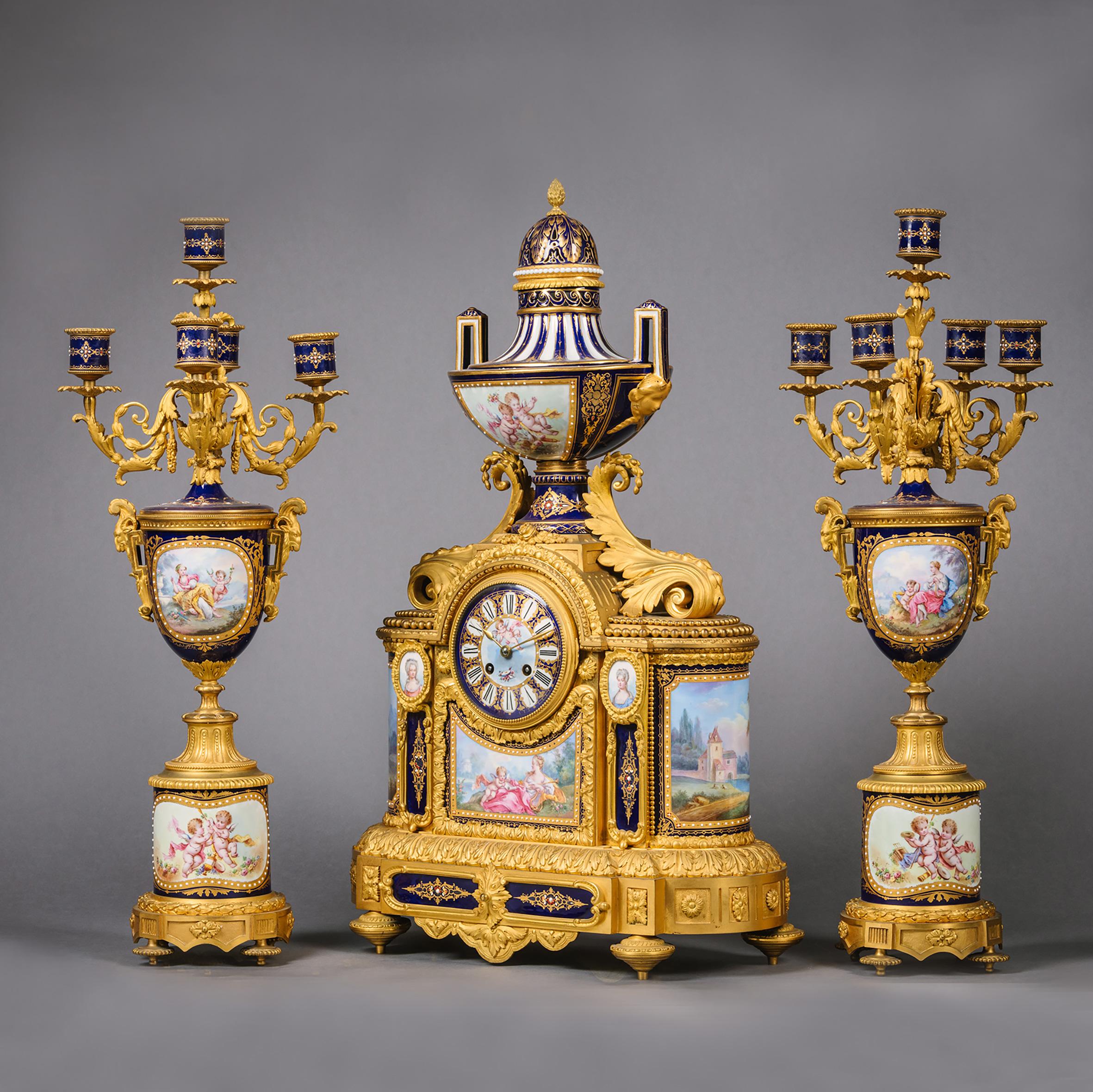 A fine Napoléon III gilt-bronze and sèvres style cobalt blue ground 'Jewelled' Porcelain Three-Piece Clock Garniture

Comprising a mantel clock and a pair of five-light vase candelabra.

The clock surmounted by an urn fine painted with putti and