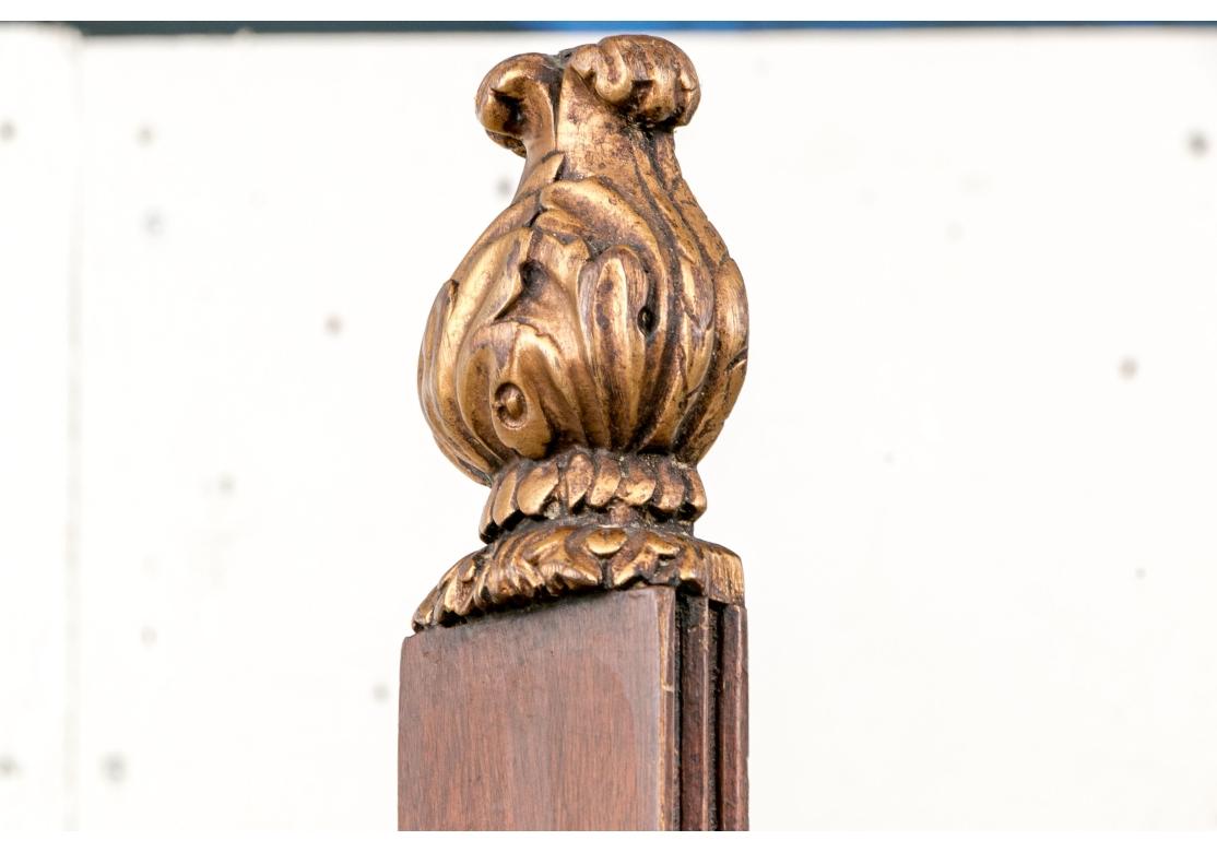 Caballete de estilo Napoleón III tallado en caoba y dorado ornamentado, de altura regulable. El caballete tiene un respaldo central coronado por un remate de bellota dorada, flanqueado por dos columnas doradas y talladas regimentalmente. La