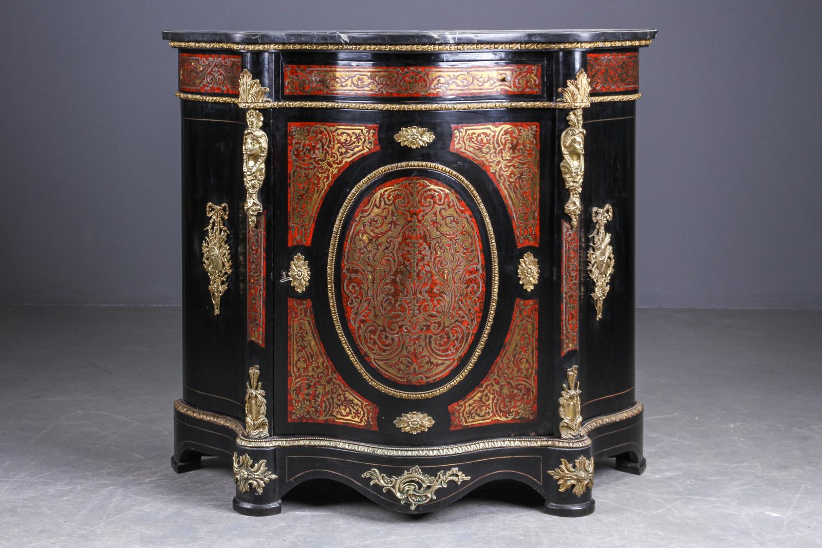 Stile Napoleone III. Armadietto, cassetto nella parte superiore, porta con serratura dietro la quale si trova un ripiano. Corpo laccato e lucidato scuro, decorato con fascia Intarsia in ottone, dettagli in bronzo dorato. Top di marmo nero variegato.