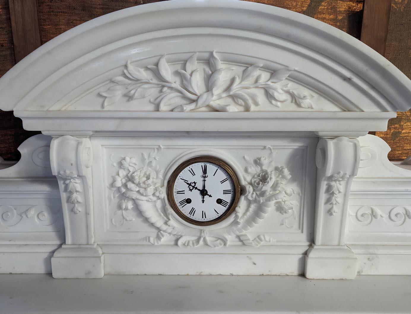 This Napoleon III style mantelpiece was made in Statuary marble in the 19th century. It includes many Renaissance inspired elements. It features an imposing mantel top, also in marble. It is crowned by a semi-circular pediment adorned with two