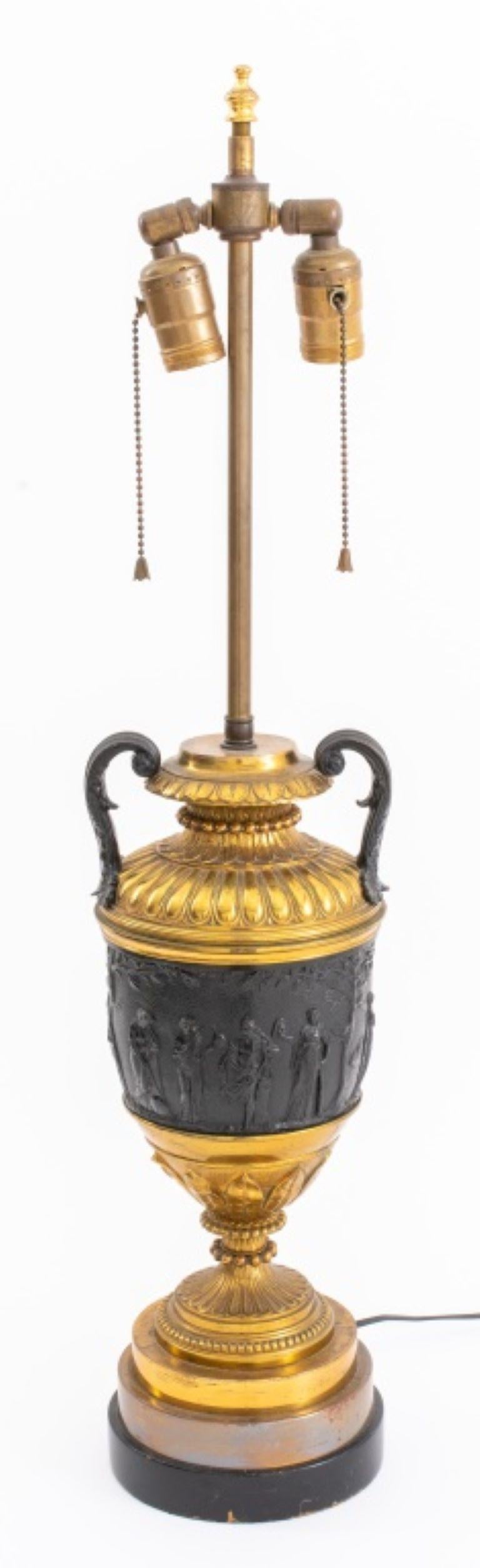 Napoleon III style neoclassical manner urn mounted as a lamp, after Louis XVI models, the gilt brass gadrooned top above a frieze depicting Bacchic scenes on a leaf-tip cast socle above a round base.