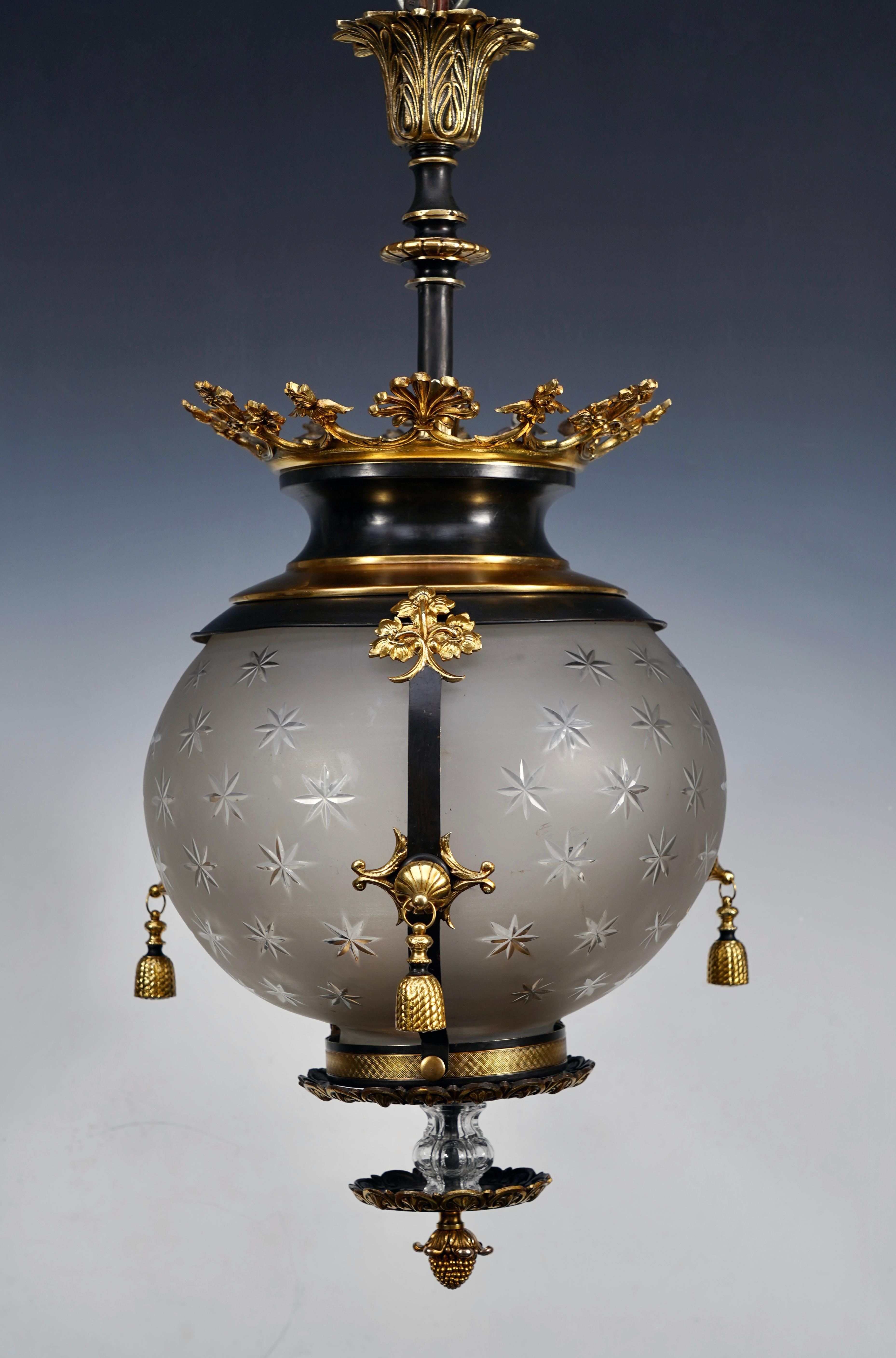 Elegant Napoleon III period lantern in patinated bronze with gold highlights and crystal. The central shaft, in the shape of a globe engraved with stars, is surrounded by three bands decorated with a central pompom, and topped with a leafy crown.
