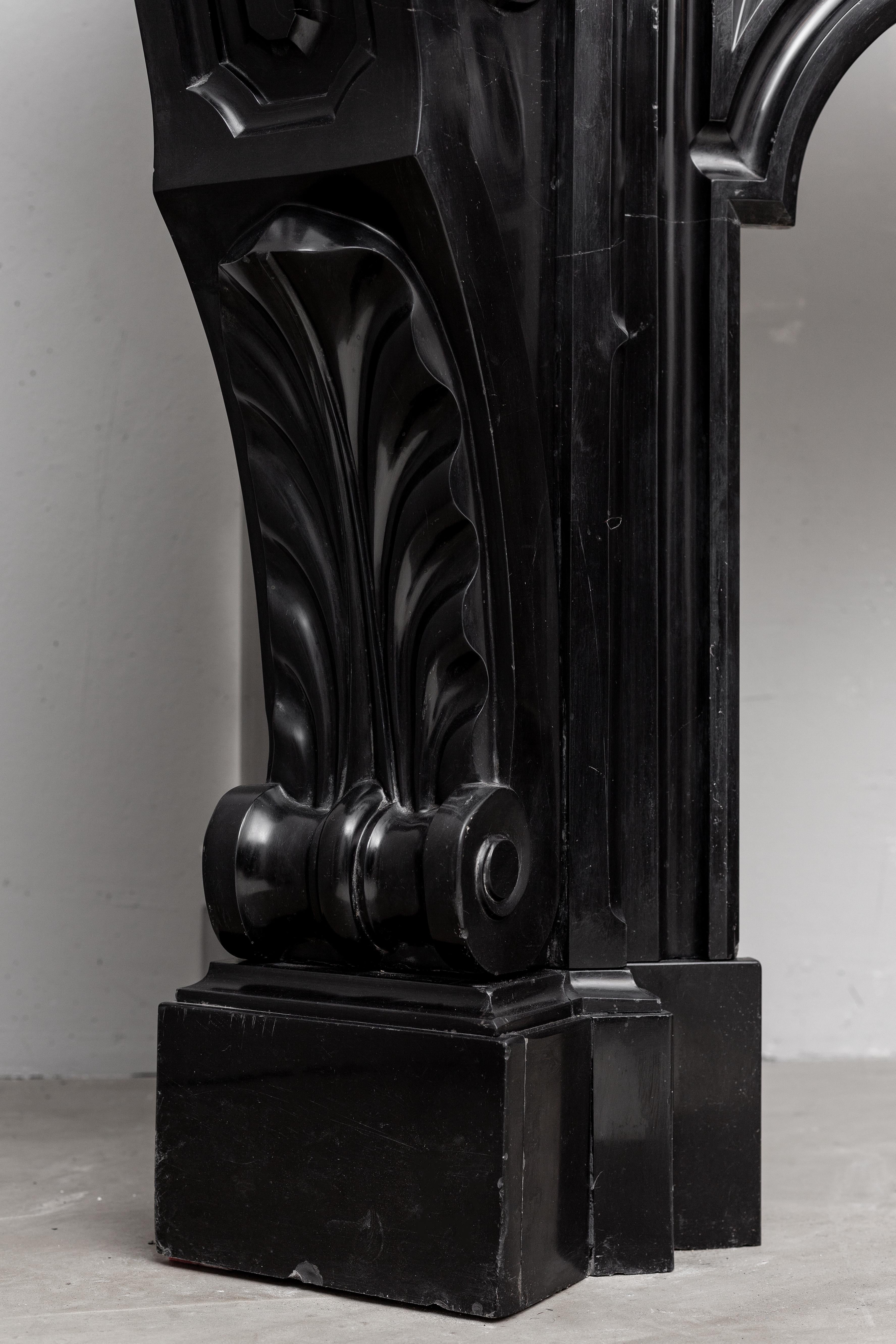 A magnificent marble fireplace wrapped in black marble: “Noir de Mazy”. An elegant combination of craftsmanship and distinctive styles. Everything about this mantelpiece is right, the round shapes of the decorated interior linteel make it a