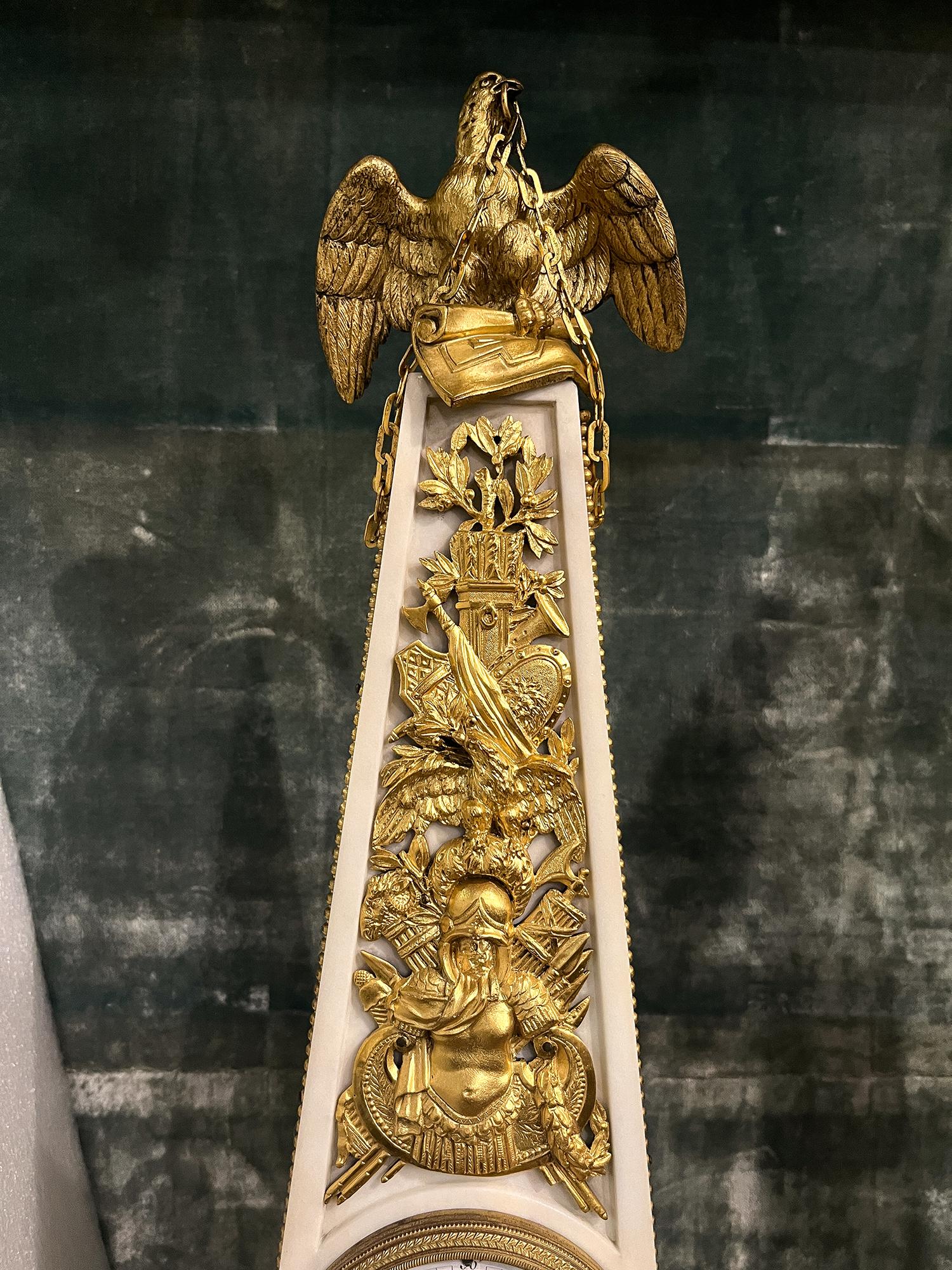 A Louis XVI style gilt bronze and marble obelisk clock with Napoleonic Military theme. Three crisply cast French Imperial Eagles adorn the clock and refer to the figure of an eagle on a staff carried into battle as a standard by the Grande Armée of