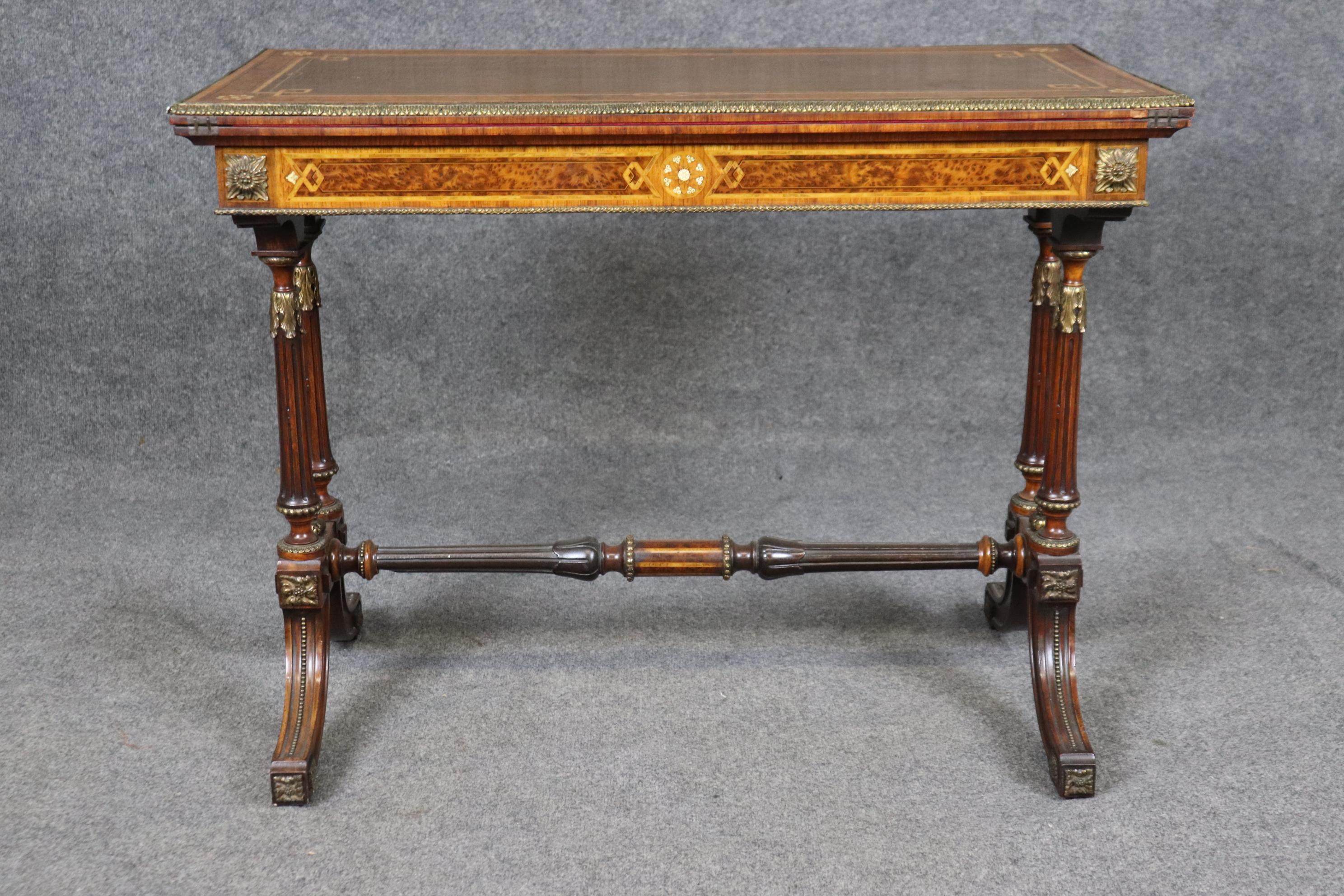 This is a spectacular mixed woods inlaid games table in the Napoleonic taste with satinwood that simply shimmers on top and burled walnut as well as ivory and bronze everywhere. This is a superb table and just beautifully done. The table opens and