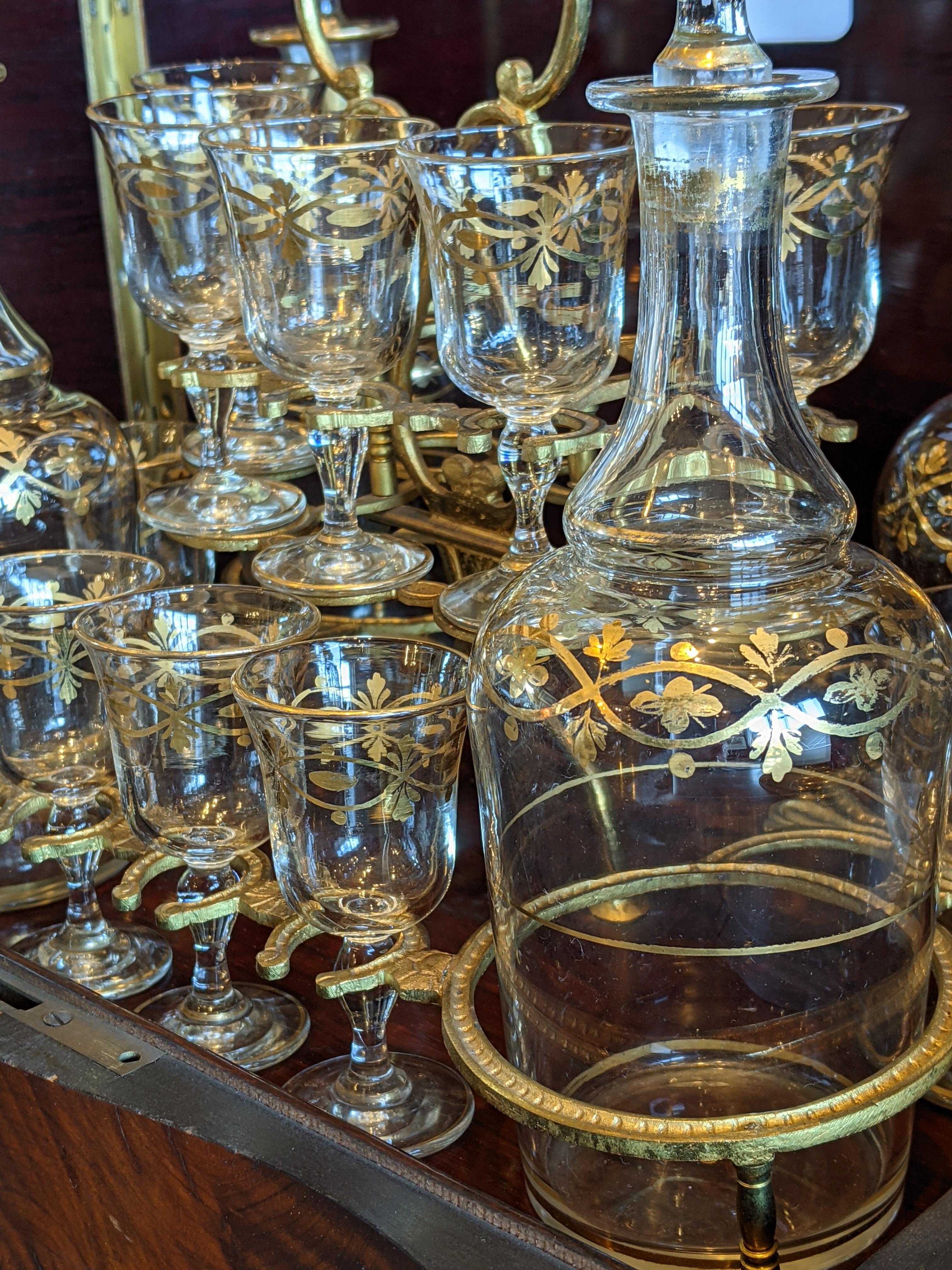 Napoleonic Tantalo liqueur cabinet, mid-19th century, in elm briar, brass and crystal glasses/bottles with gold filaments.
Six shot glasses missing.
