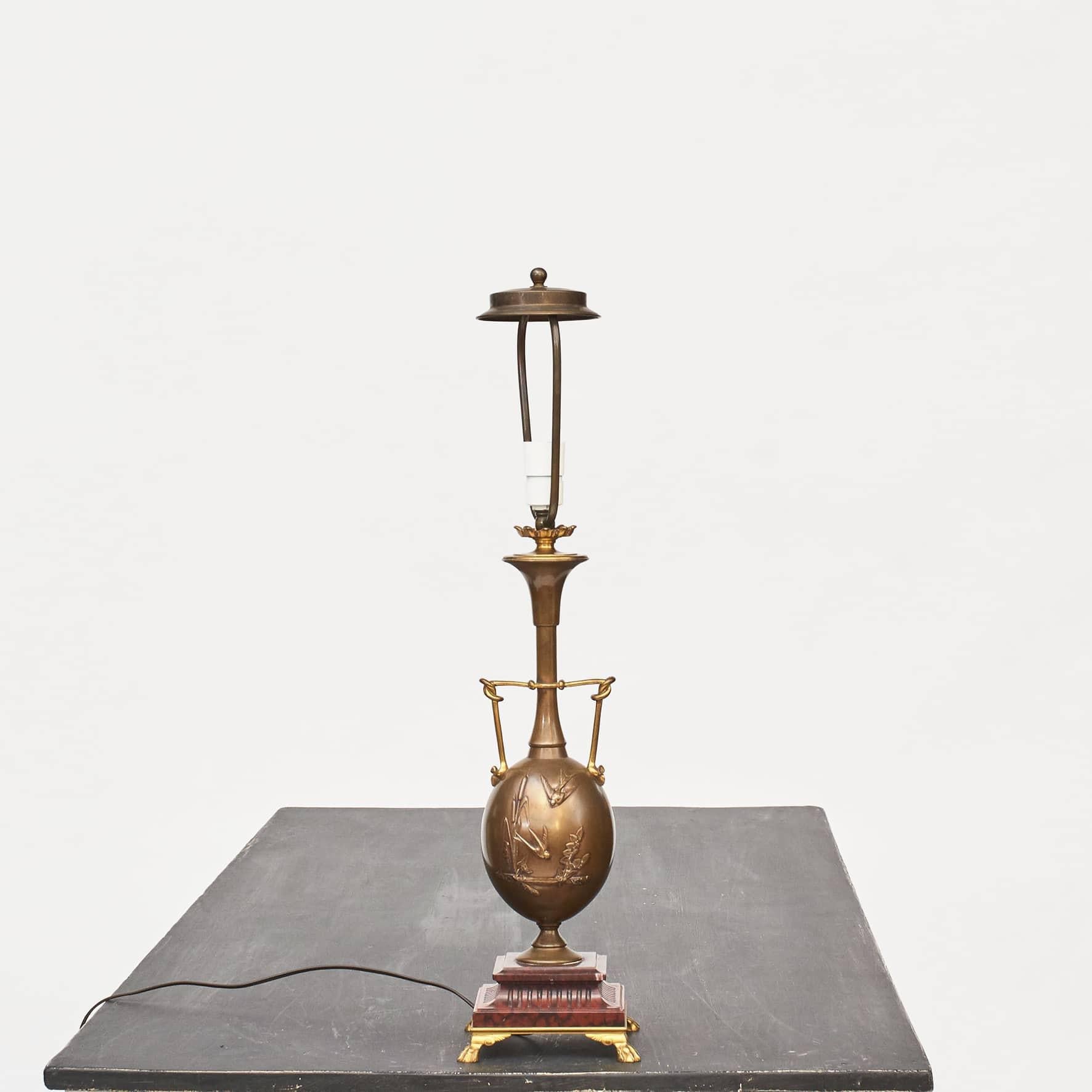 Lampe de table à vase en bronze doré et patiné, équipée pour l'électricité. Avec un décor en relief d'hirondelles et de végétation reposant sur une base en marbre rouge 