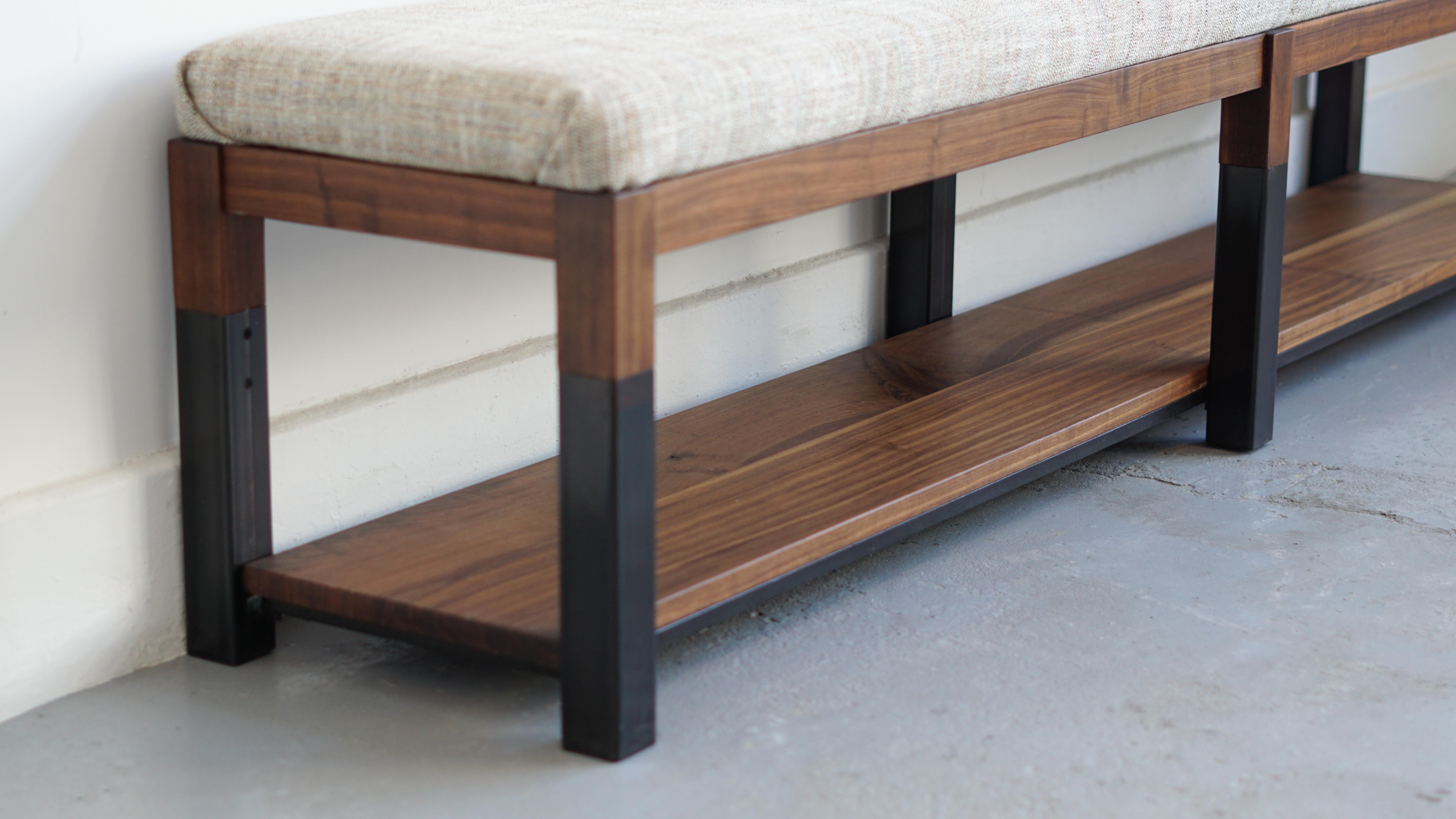 Black walnut and steel meet to form a continuous base for this bench / ottoman with a custom upholstered top. Fabric choice can be fully customizable.