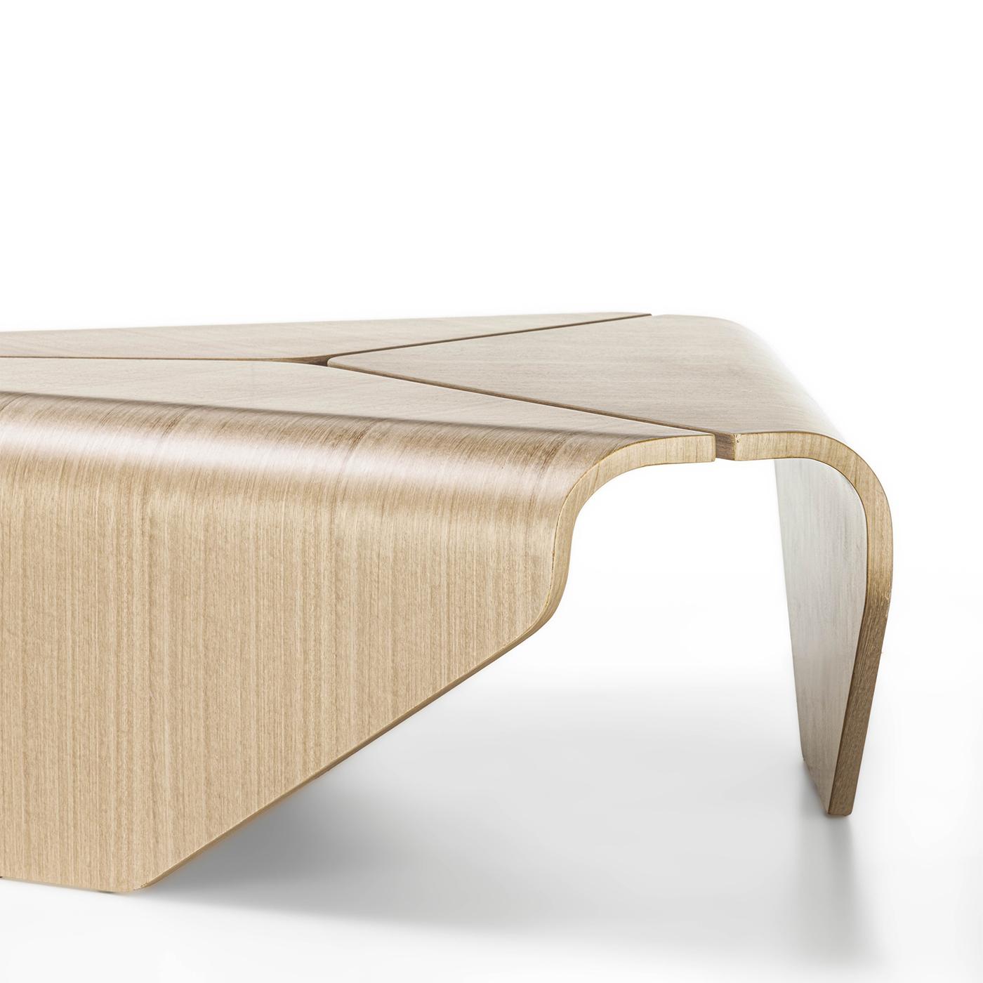 Cleverly bent to achieve a fluid, freestanding silhouette brimming with sculptural charm, three dynamically cut elements compose this captivating coffee table. The solid and bright eucalyptus frame flaunts linear woodgrain, attesting to the table's