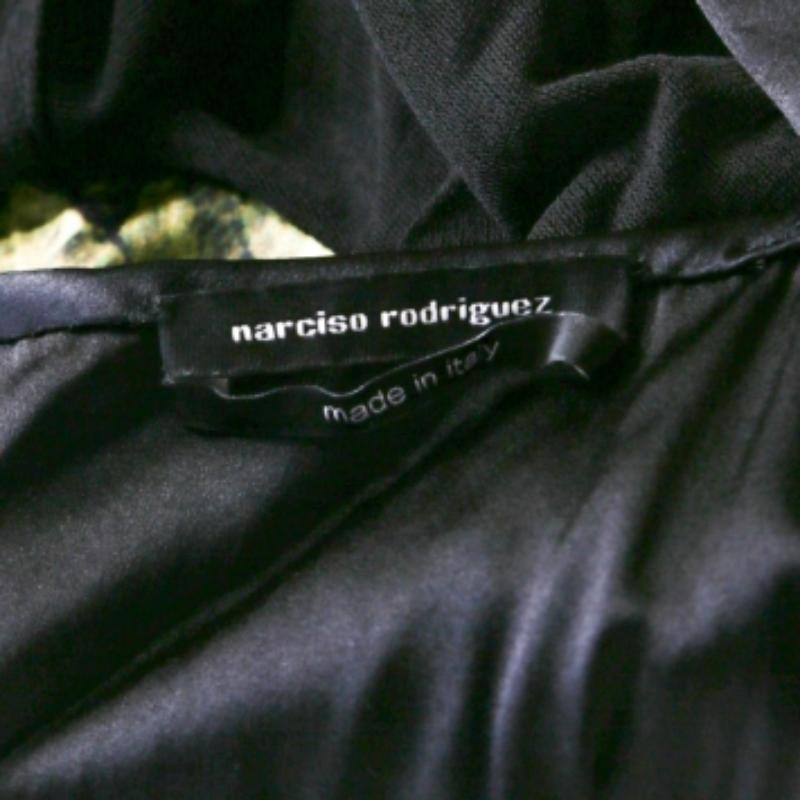 Questo abito di Narciso Rodriguez, magistralmente realizzato con tessuti di qualità, è un riflesso della moda femminile. È stato progettato con i colori del verde e del nero, una cerniera posteriore e una maglia a rete. L'abito è la giusta fusione