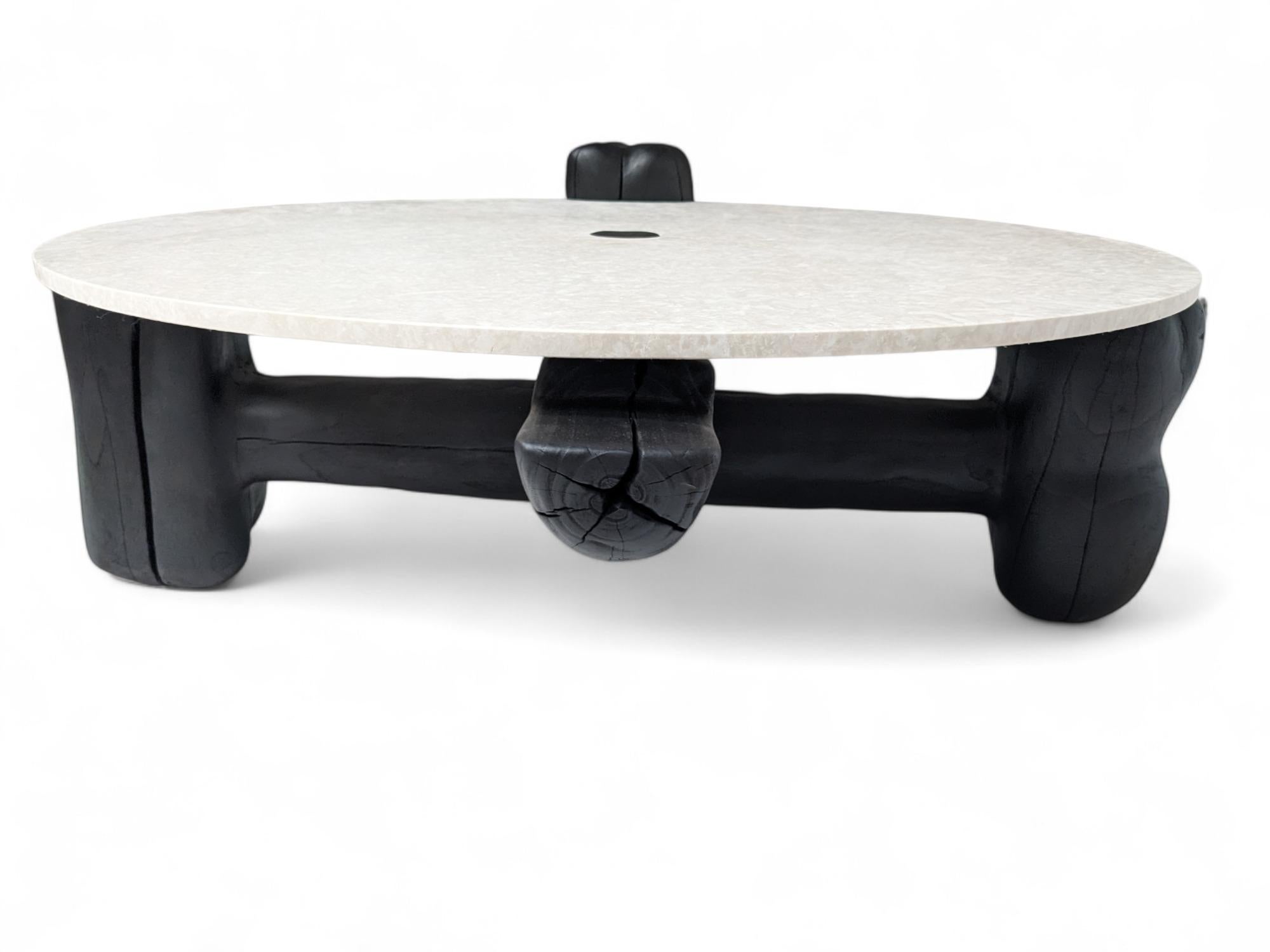 Narco Teak Collection Centre Table Round by AMBER x IÑIGO CALLEJA
Dimensions: D 130 x H 45 cm. 
Materials: Dry Teak Trunks Base, charred and stained pitch black, Ivory cream Marble top, matt finish.

Iñigo Calleja is an engineer, designer and