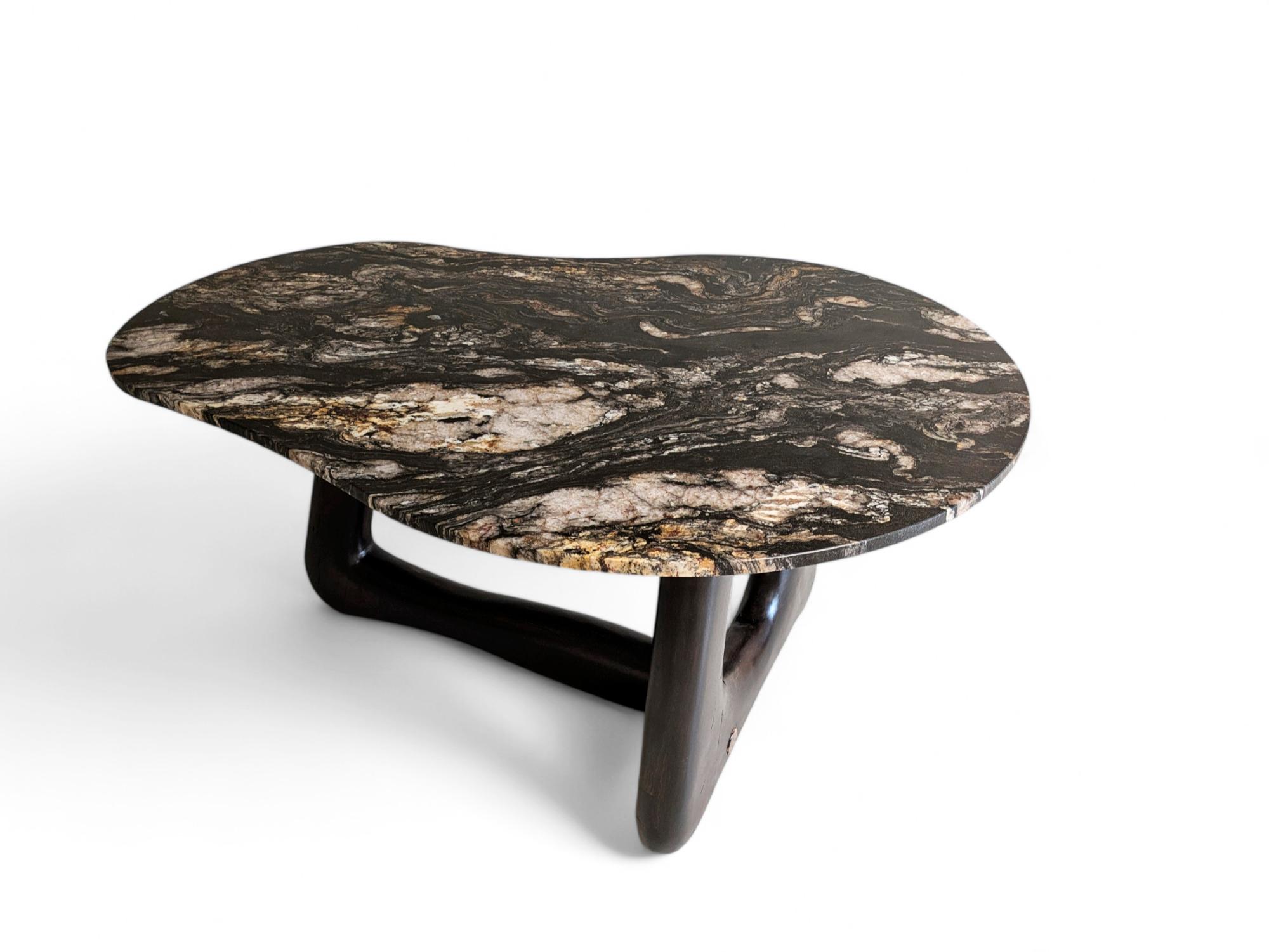 Narco Teak Collection Dining Table Pebble by AMBER x IÑIGO CALLEJA
Dimensions: W 150 x D 110 x H 75 cm. 
Materials: Dry Teak Trunks Base, Emperor Black Granite Top, charred and stained pitch black, matt finish.

Also available in Ivory cream Marble