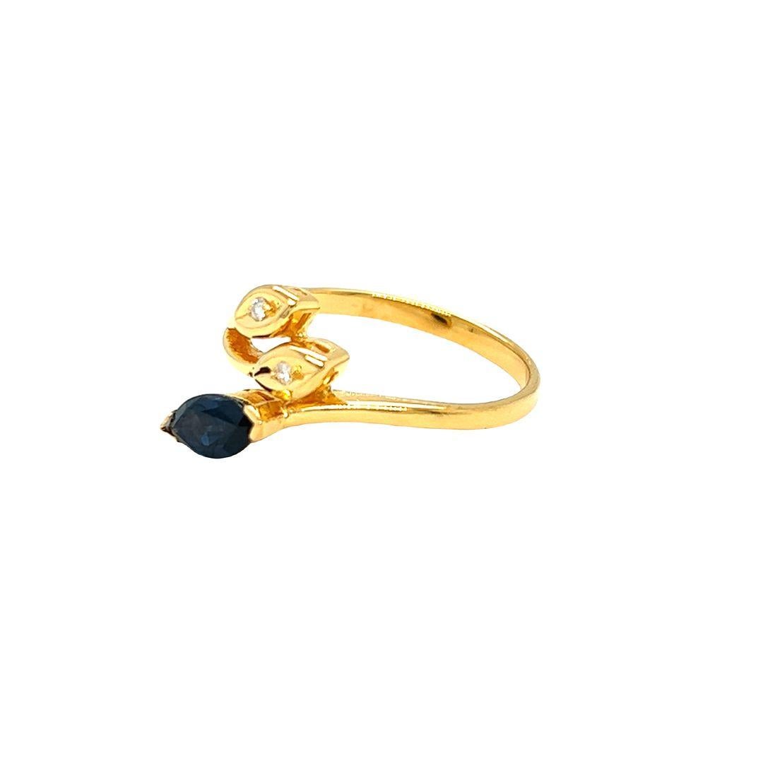 14K yellow gold fashion ring showcases a marquise-cut sapphire in a striking bright blue hue, beautifully placed diagonally along the ring's shank. The vibrant blue sapphire measures approximately 6 mm x 4.5 mm, weighing 0.65 carat. This bypass ring