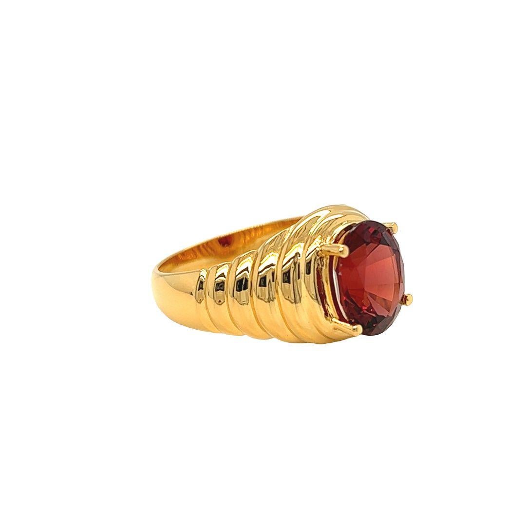 A stunning 10mm x 8mm oval shaped garnet weighing 4 carats sits atop a fluted, ribbed textured band, creating an eye-catching ring. At 11.8mm in length and 6.8mm in height (from finger when worn), this size 7 ring is designed and crafted by Nari