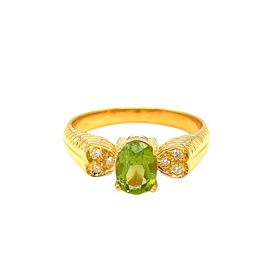 Crafted in 14K yellow gold by Nari Fine Jewels, this oval-shaped peridot gemstone measures 7mm x 5mm and weighs 1 carat. On either side, three small round diamonds are set in heart-shaped stations totaling 0.06 carat. The heart-shaped stations give