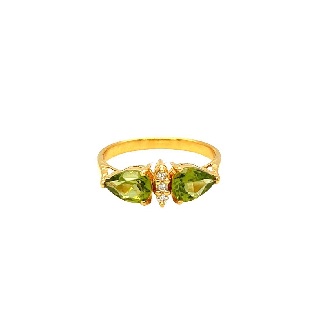 Crafted with 14k yellow gold, this ring features two east-west pear cut peridots totaling 1.60 carats and three diamonds nestled in the center. With a face measuring 6.6 mm and a 4.3 mm rise from finger, this peridot ring exudes a luxurious look for