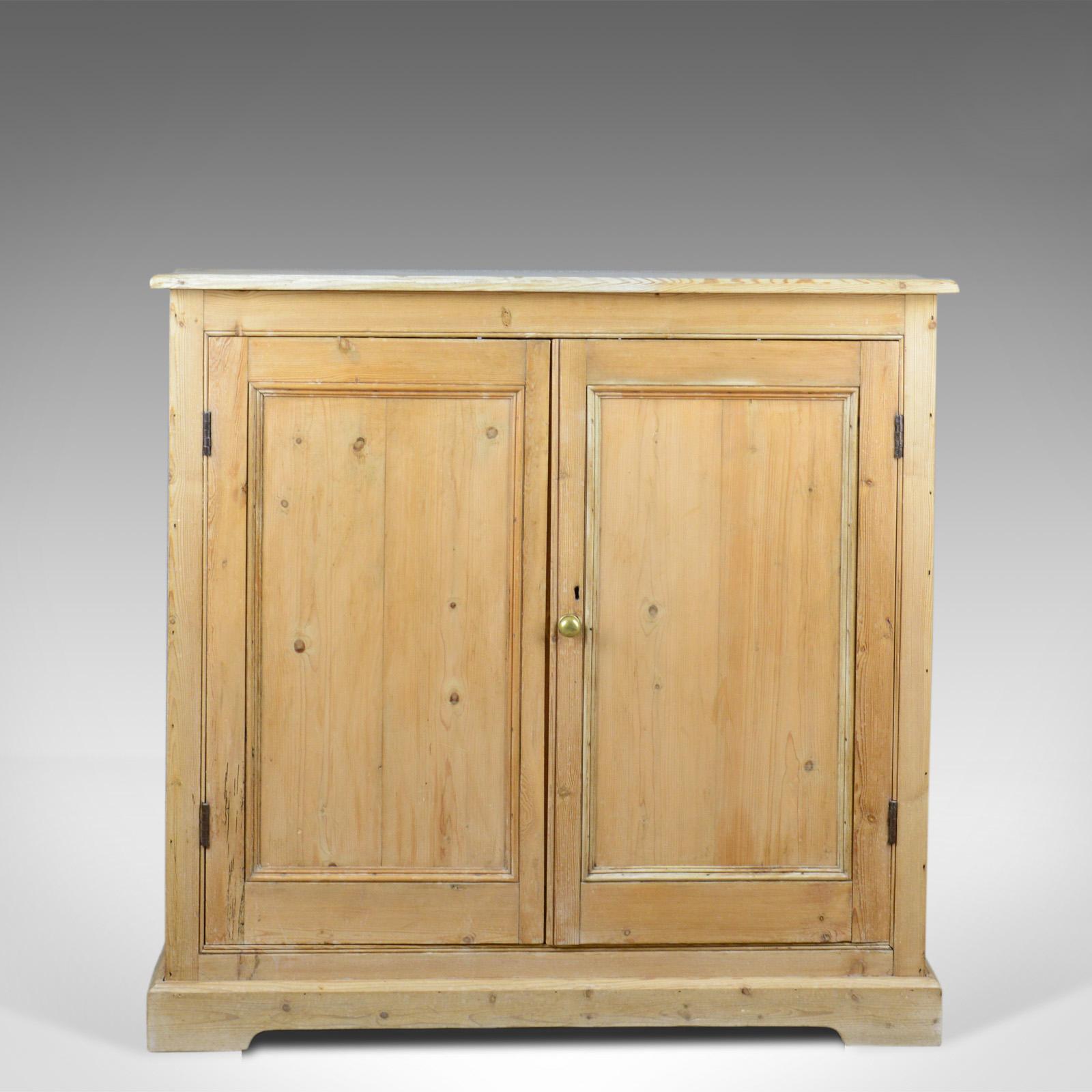 This is a narrow antique pine cupboard, an English, Victorian kitchen cabinet dating to circa 1850.

Chamfered edged top over pine cupboard
Grain interest with a desirable aged patina
Standing upon a continuous, shaped plinth base

A pair of