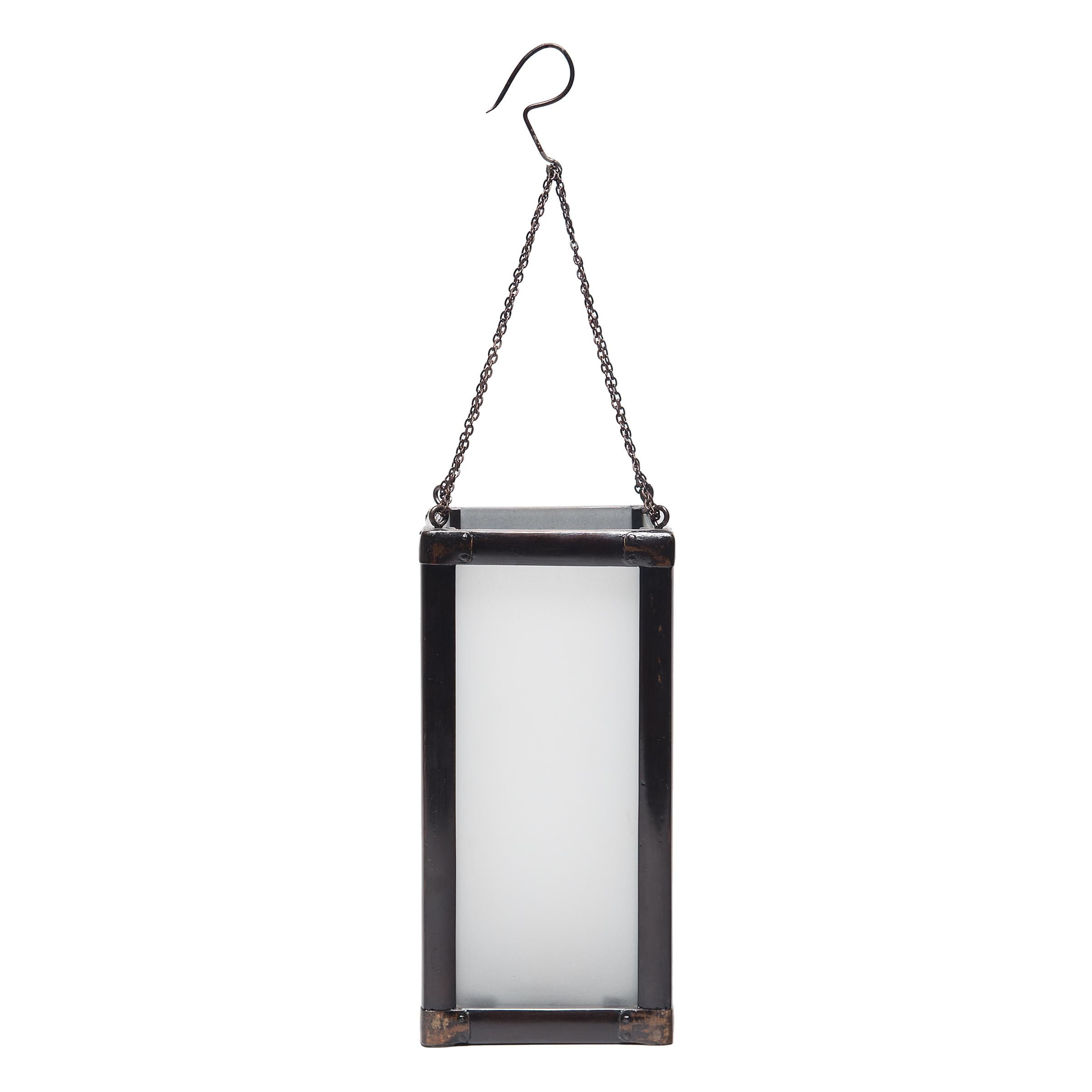 Encadrée en bois noir, cette lanterne carrée du XIXe siècle diffuse une douce lumière à travers le verre dépoli. Affichant la simplicité raffinée que l'on retrouve dans les meubles de la même époque, la lanterne illumine les intérieurs modernes avec
