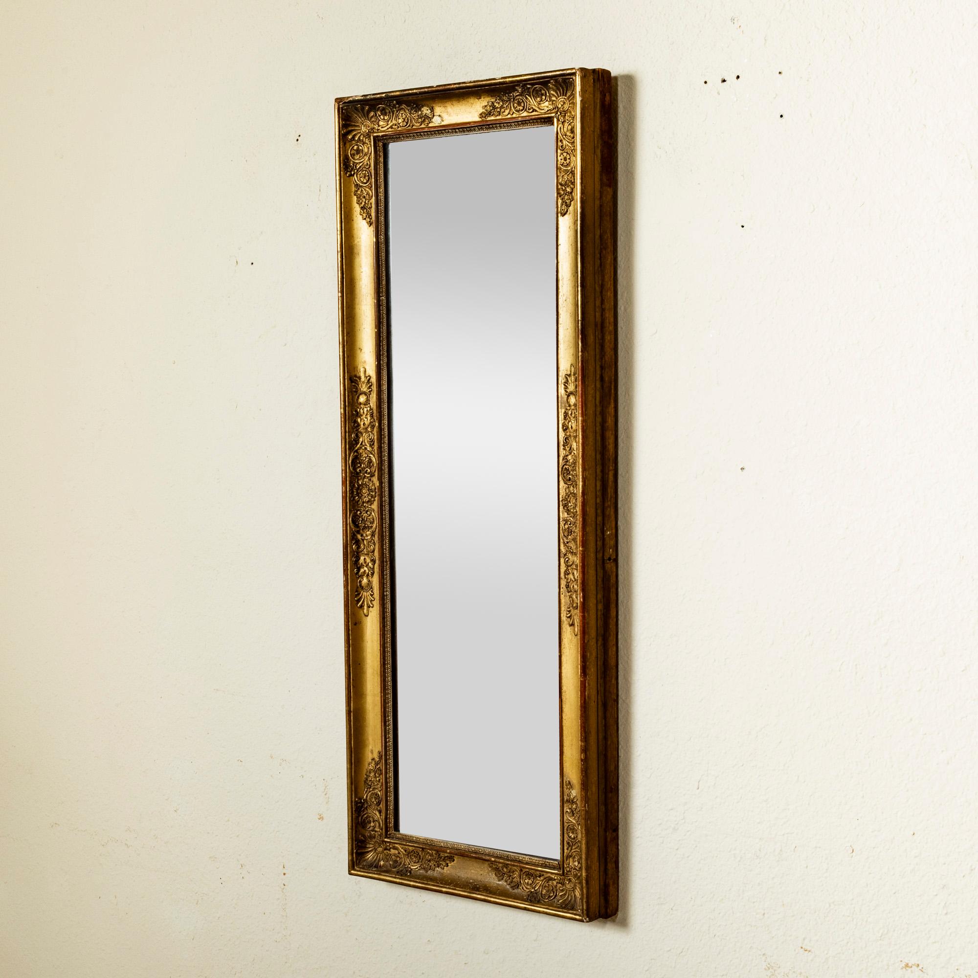 Dieser Spiegel aus vergoldetem Holz aus dem frühen neunzehnten Jahrhundert ist mit seinem originalen Quecksilberglas ausgestattet. Der Rahmen ist mit Palmetten, Rankenwerk, Rosetten und Eichenblättern an den Ecken verziert, und der Spiegel ist von