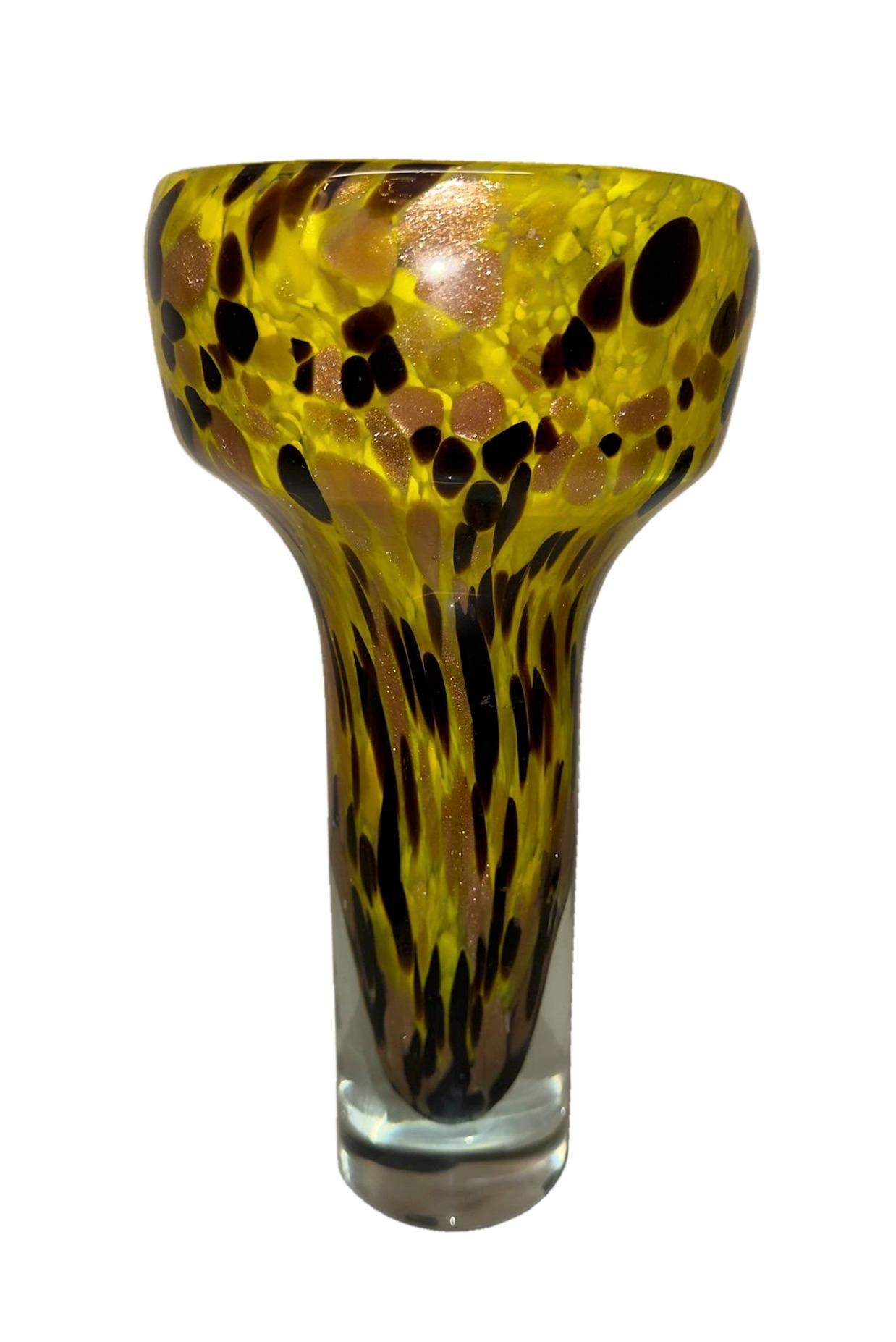 Diese lebendige und ausdrucksstarke Vase aus mundgeblasenem Murano-Glas ist ein kühnes Fest venezianischer Kunstfertigkeit und zeitgenössischer Farben. Mit ihrem schmalen gelben Hals, der mit unregelmäßigen schwarzen und bernsteinfarbenen Sprenkeln