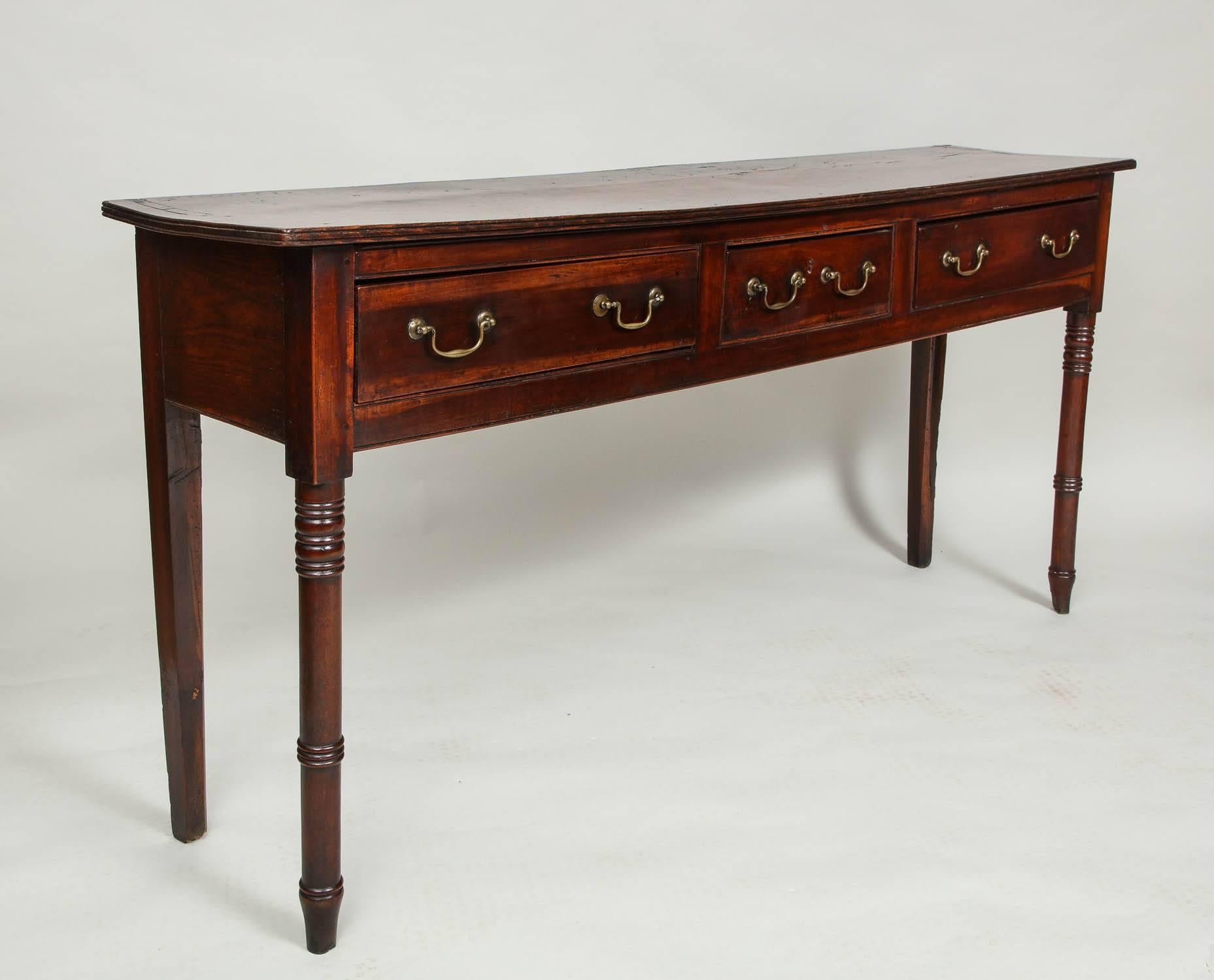 Fine early 19th century elm and fruitwood hunt board, the elm plank top with simple molded edge, over two wide and one thinner central drawer with plumwood drawer fronts having original swan neck pulls, standing on ring turned tapered front legs and