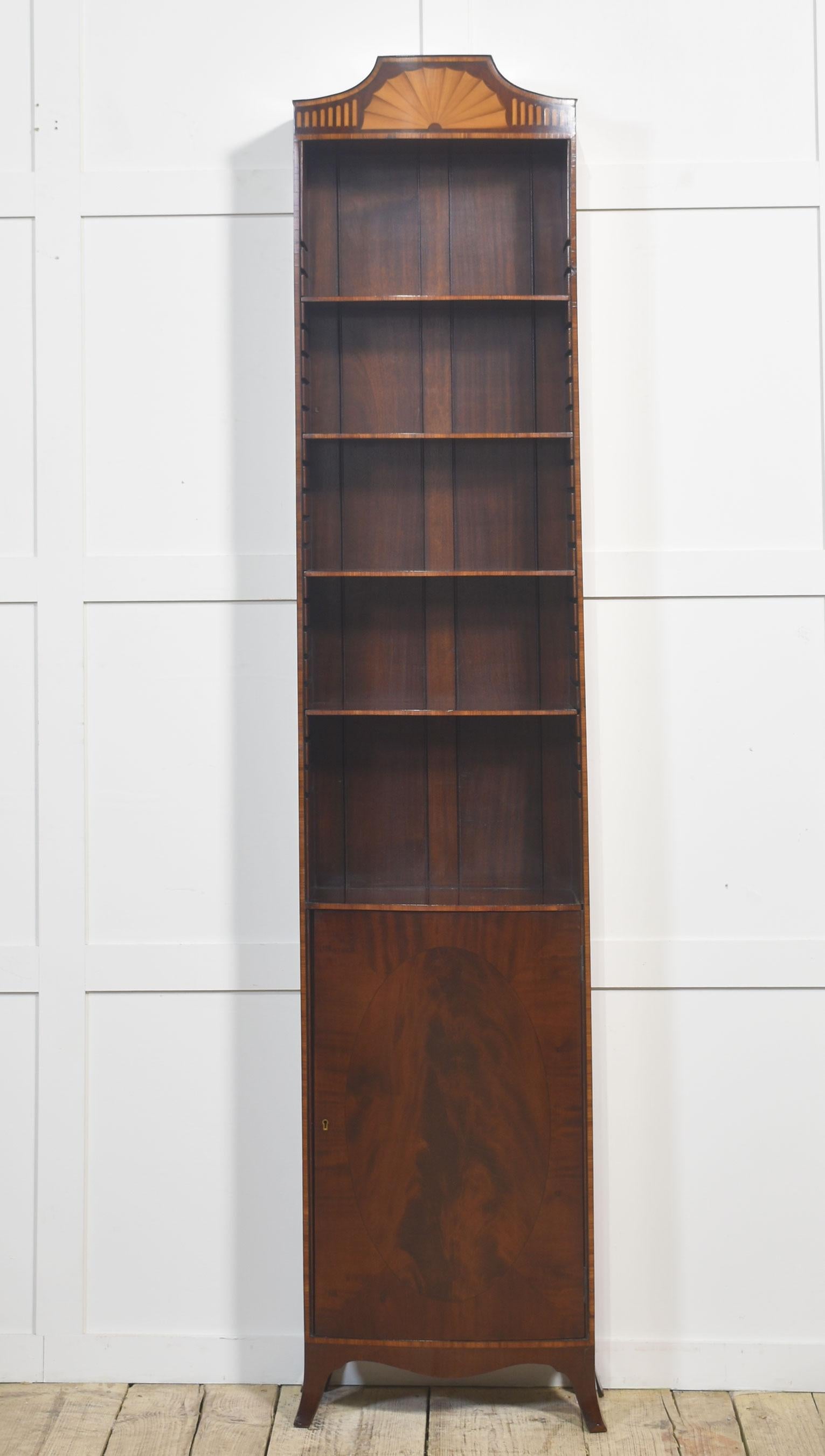 Questa elegante libreria in mogano è un bellissimo esempio di artigianato e design senza tempo. Di forma slanciata e alta, presenta un suggestivo motivo a ventaglio intarsiato sul cornicione e una porta in mogano riccamente scolpito con pannelli