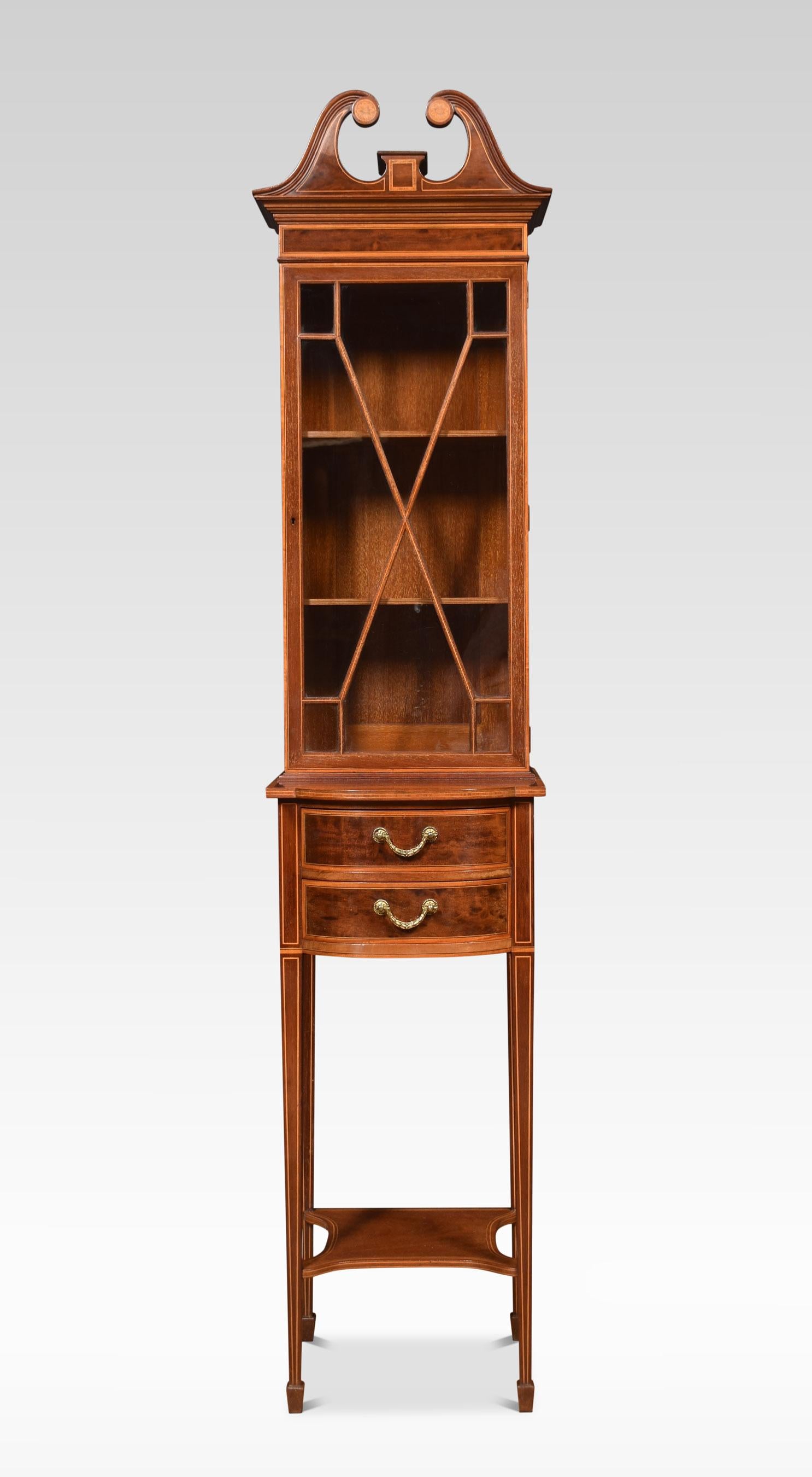 Mahogany inlaid bookcase, the swan neck pediment above the glazed door opening to reveal a shelved interior. To the base fitted with two short drawers and brass swan neck handles. All raised up on four slender tapering legs terminating in spade