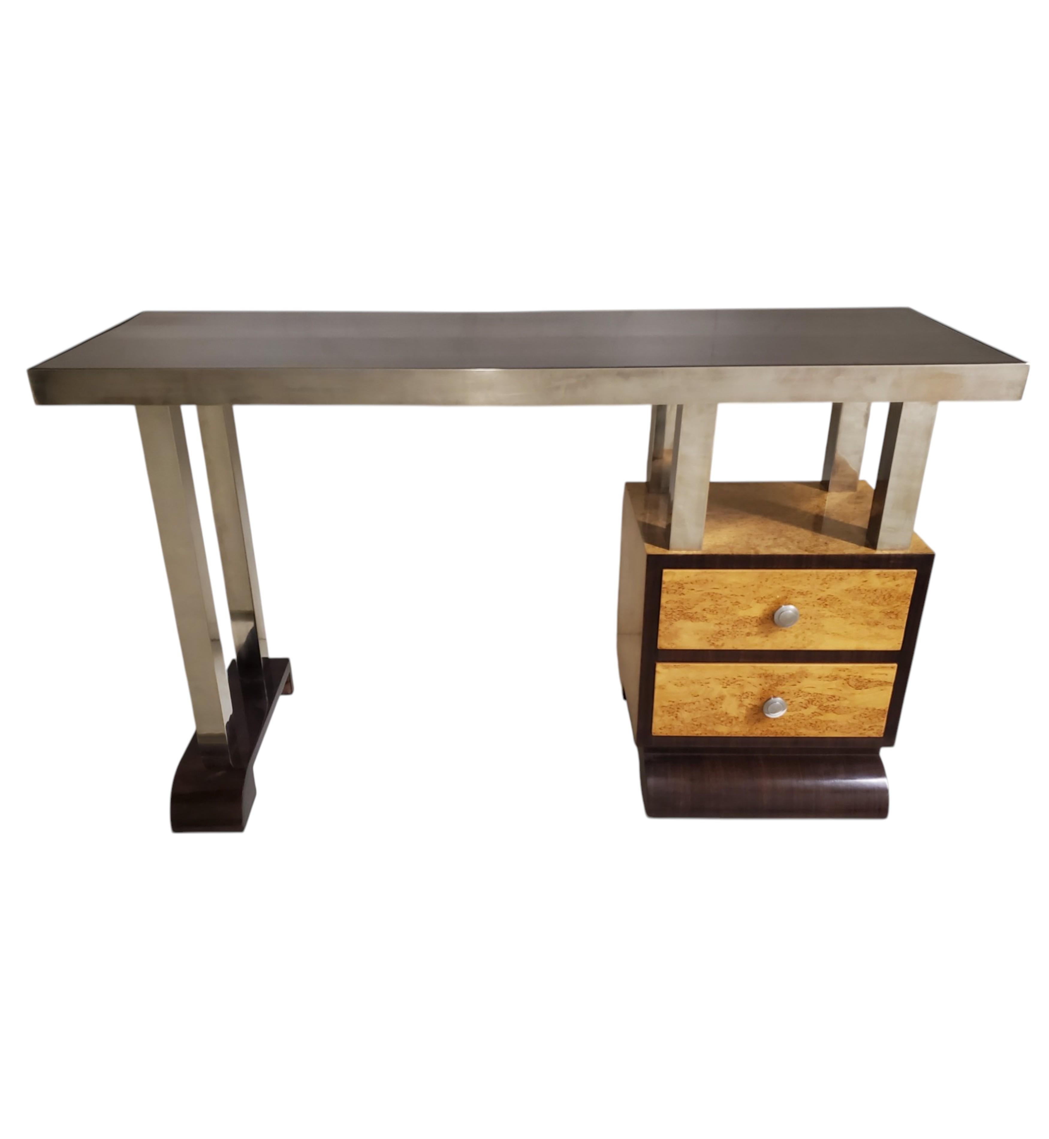 Schlanker und stromlinienförmiger französischer Art-Déco-Schreibtisch aus zweifarbigem Holz mit seitlichem Ablagefach, polierter, vernickelter Bronzebandeinfassung und passenden Vierkantrohrstützen.
Dieser minimalistische Schreibtisch verfügt über