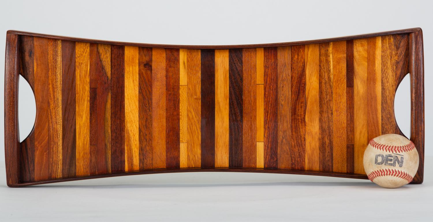 A narrow rosewood tray by Don Shoemaker for Señal, designed and produced in Mexico. This examples has bowed-in edges framed by four curved pieces of solid rosewood. There is a cut-out handle on either side of the tray. The surface features an inlay