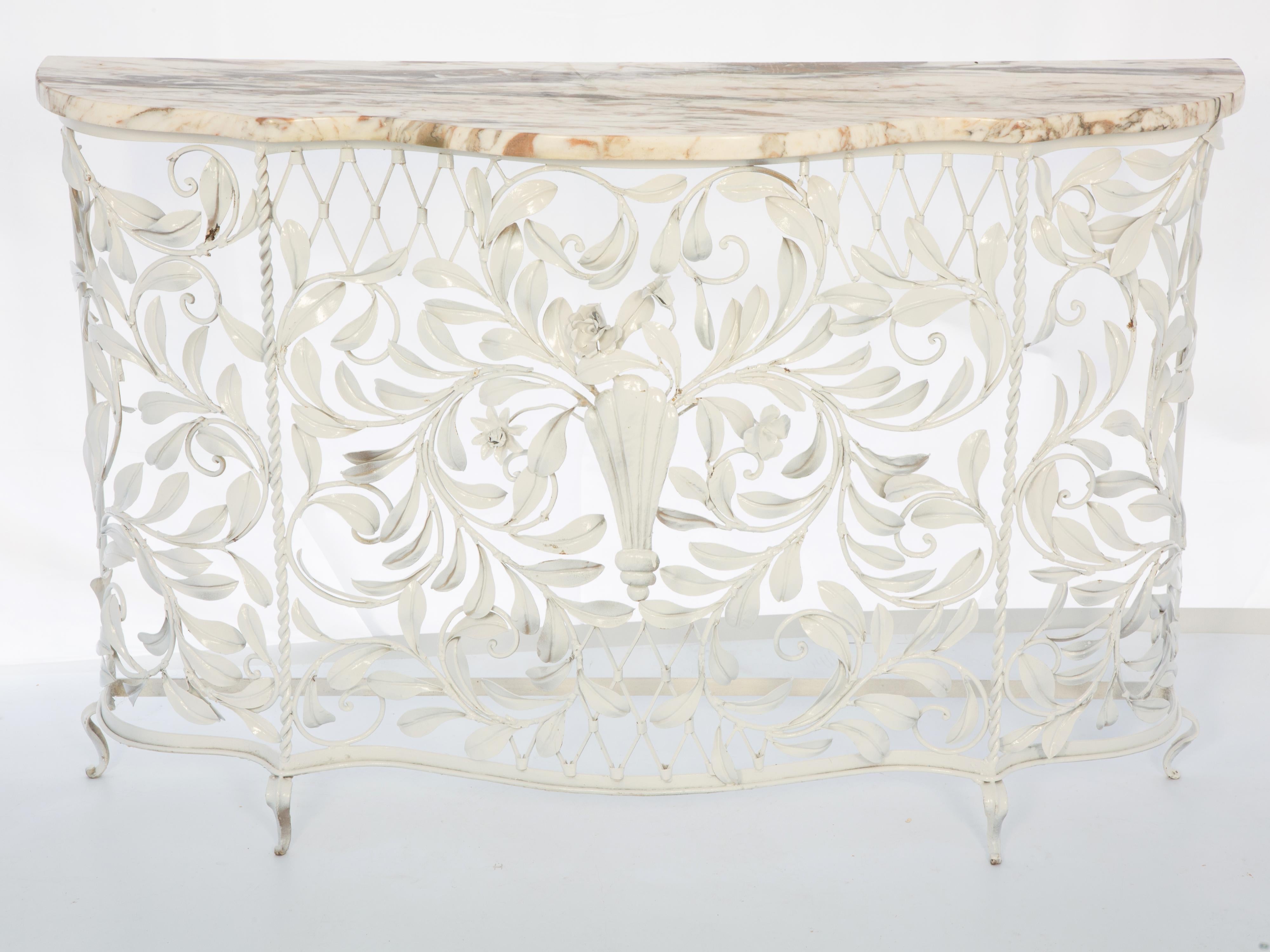 Vintage Italian console, of white enamel-painted iron having a shaped marble top. Its narrow, conforming base of wrought iron elaborately decorated with foliate scrolling, centered by a flower-filled, reeded cartouche, raised on small scroll feet.