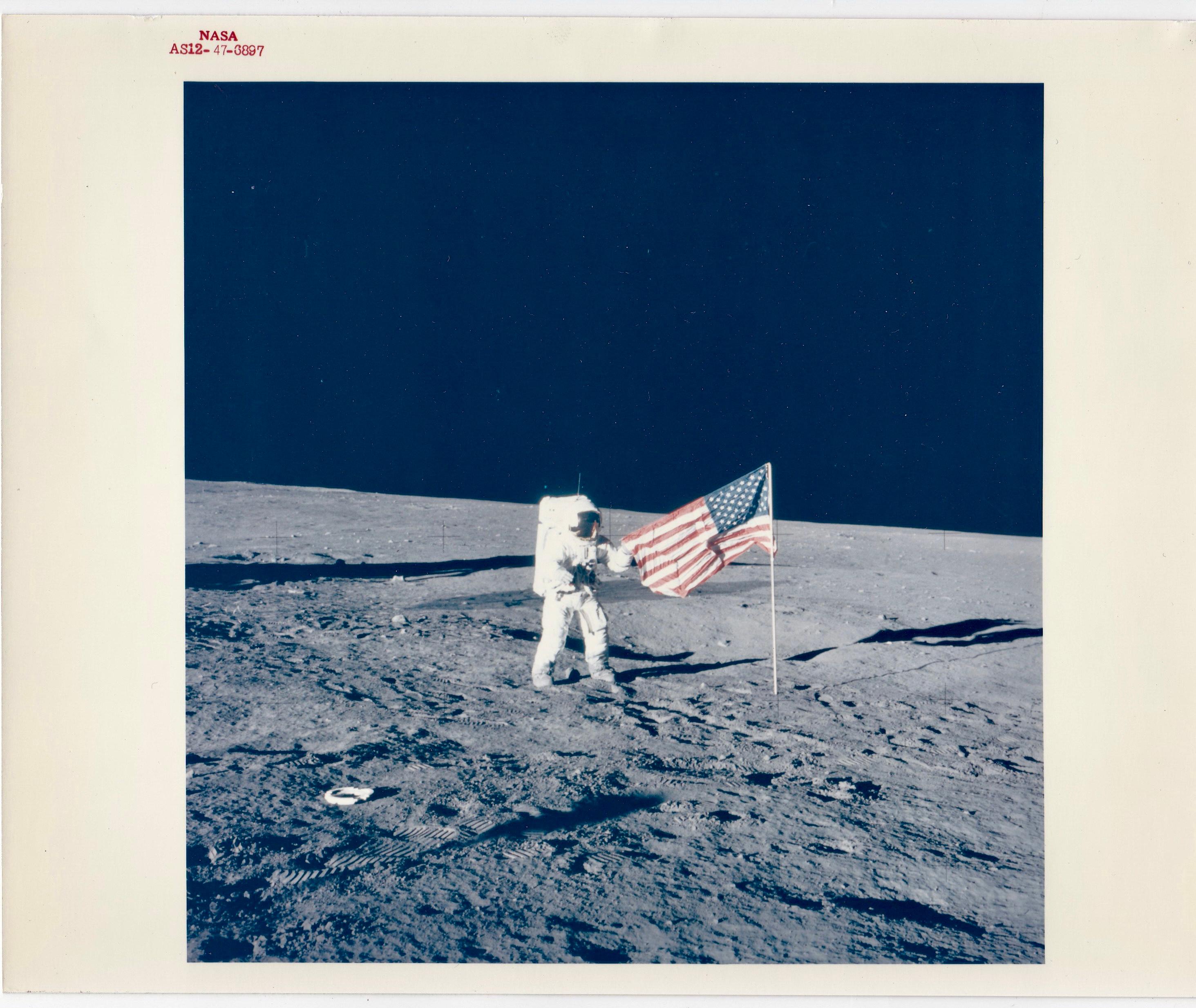 Der NASA-Astronaut und Kommandant der Apollo 12, Pete Conrad JR, wird von seinem Kollegen Alan Bean fotografiert und posiert mit der amerikanischen Flagge, nachdem er und Bean sie auf dem Mond aufgestellt haben.

Es handelt sich um ein 8" x 10"