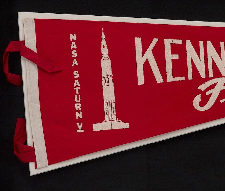 Presented is a vintage felt pennant commemorating the NASA Cape Kennedy Space Center and Saturn V rocket. The pennant dates to circa 1966-1973. “Kennedy Space Center” is printed in block white lettering across the width of the pennant. In cursive