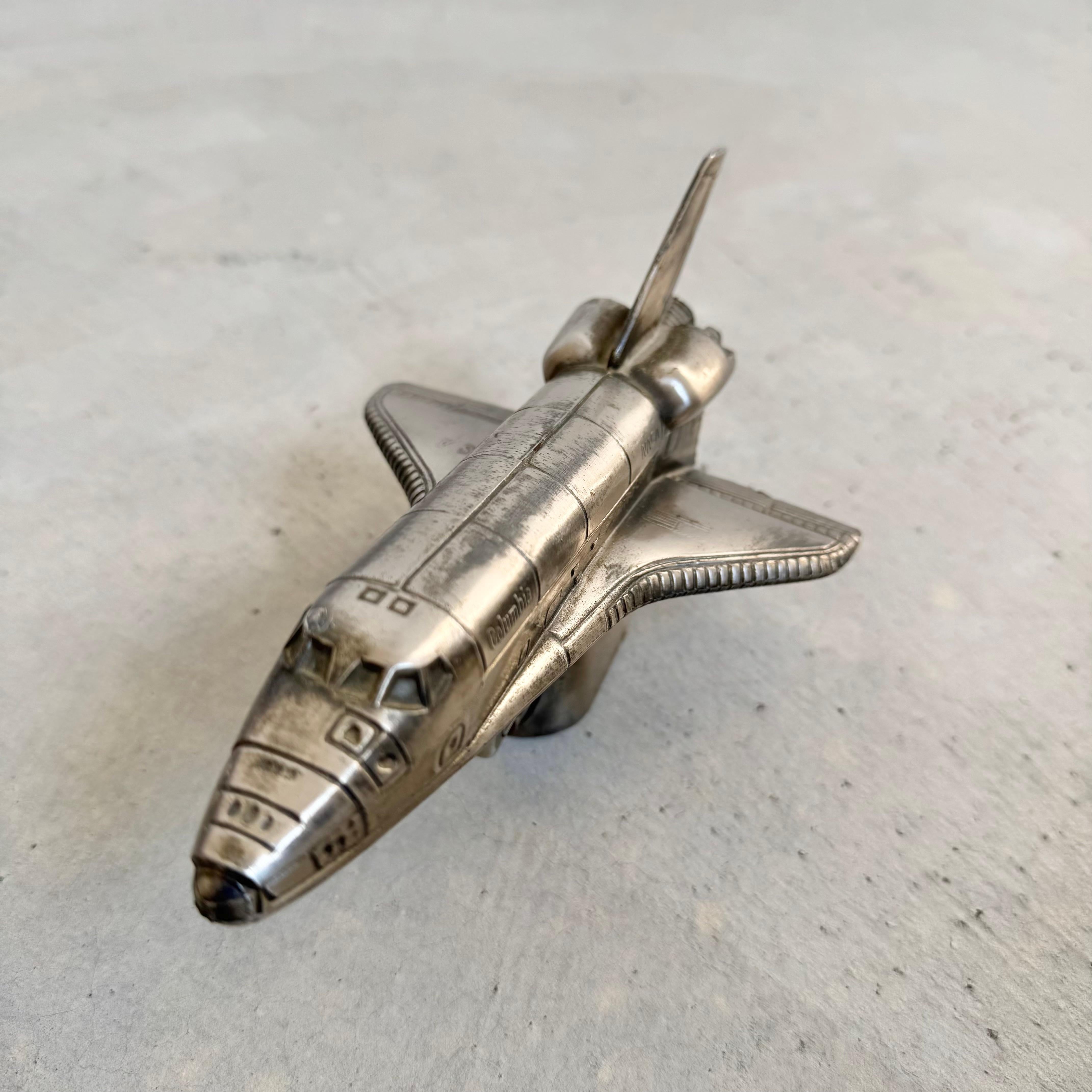 Blast off with this Nasa Space Shuttle lighter. Made in Japan, circa 1980s for Comoy's of London. Modeled after the Columbia shuttle. Great detail with badging throughout. Working lighter. Fun, desktop object. Good vintage condition with wear as
