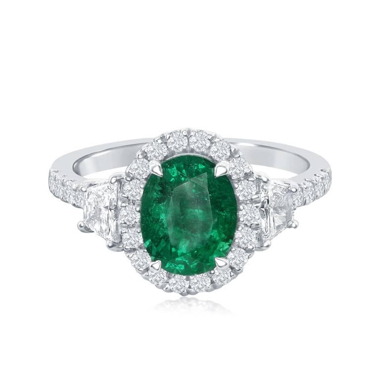 This classy and timeless ring features a beautiful and sparkly oval emerald.  The emerald is surrounded by shiny brilliant cut diamonds.  This ring also has a beautiful trapezoid diamond on each side of the center stone and round diamonds going down