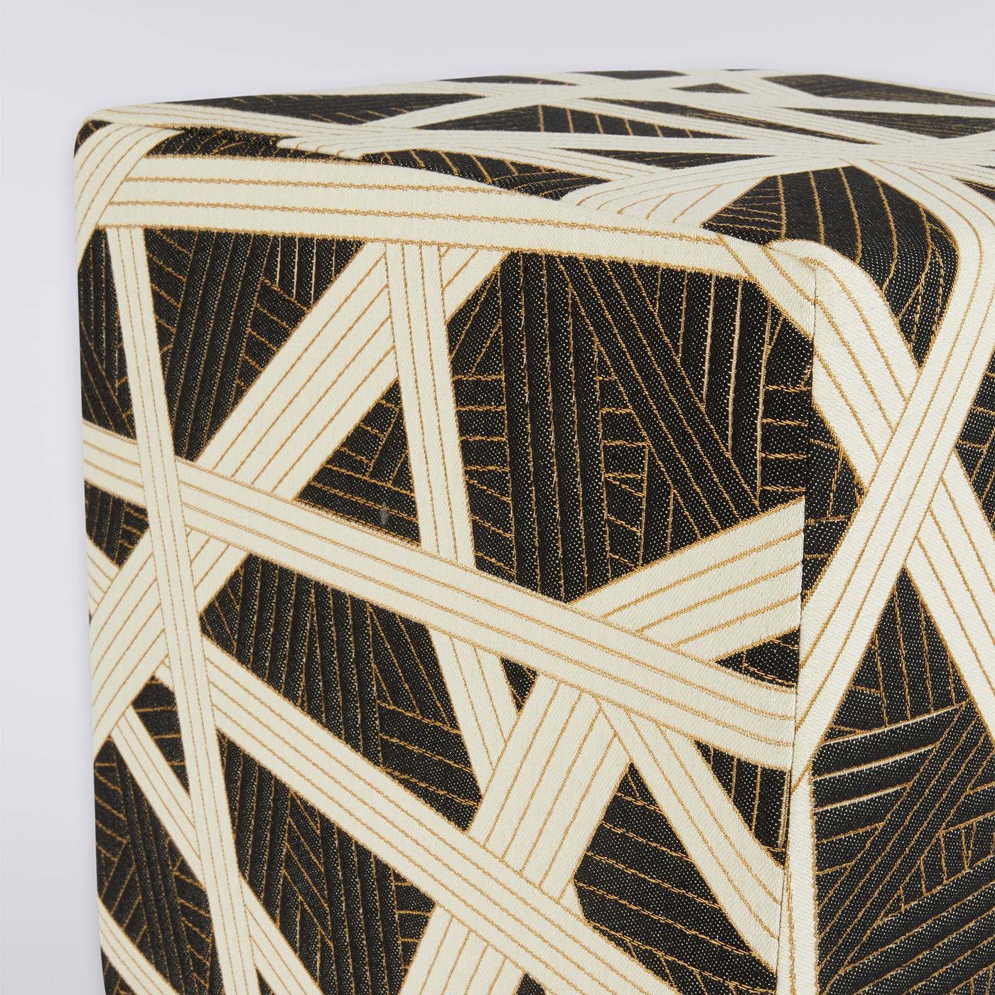 Un triomphe de bandes blanches et noires s'entrecroisant de manière complexe confère à ce pouf son dynamisme. Proposé dans une silhouette cubique d'inspiration résolument moderne, il arbore une délicieuse brillance tracée par des lignes dorées