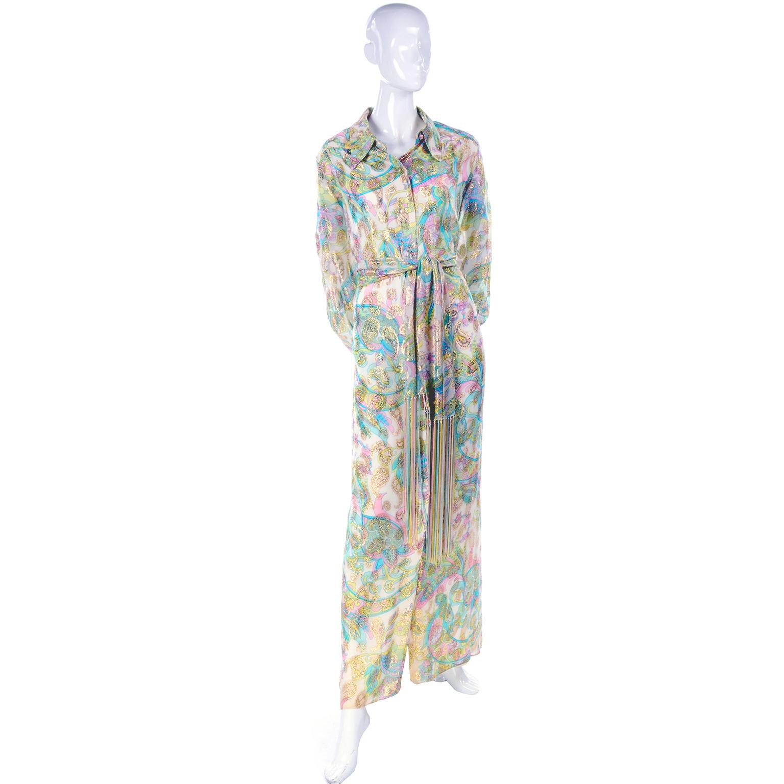 This beautiful vintage dress has sparkling gold metallic paisley designs atop swirling floral designs in pastel green, yellow, blue and pink! Made by Nat Kaplan Couture in the 1970's, this long shirt dress buttons entirely down the front, and has