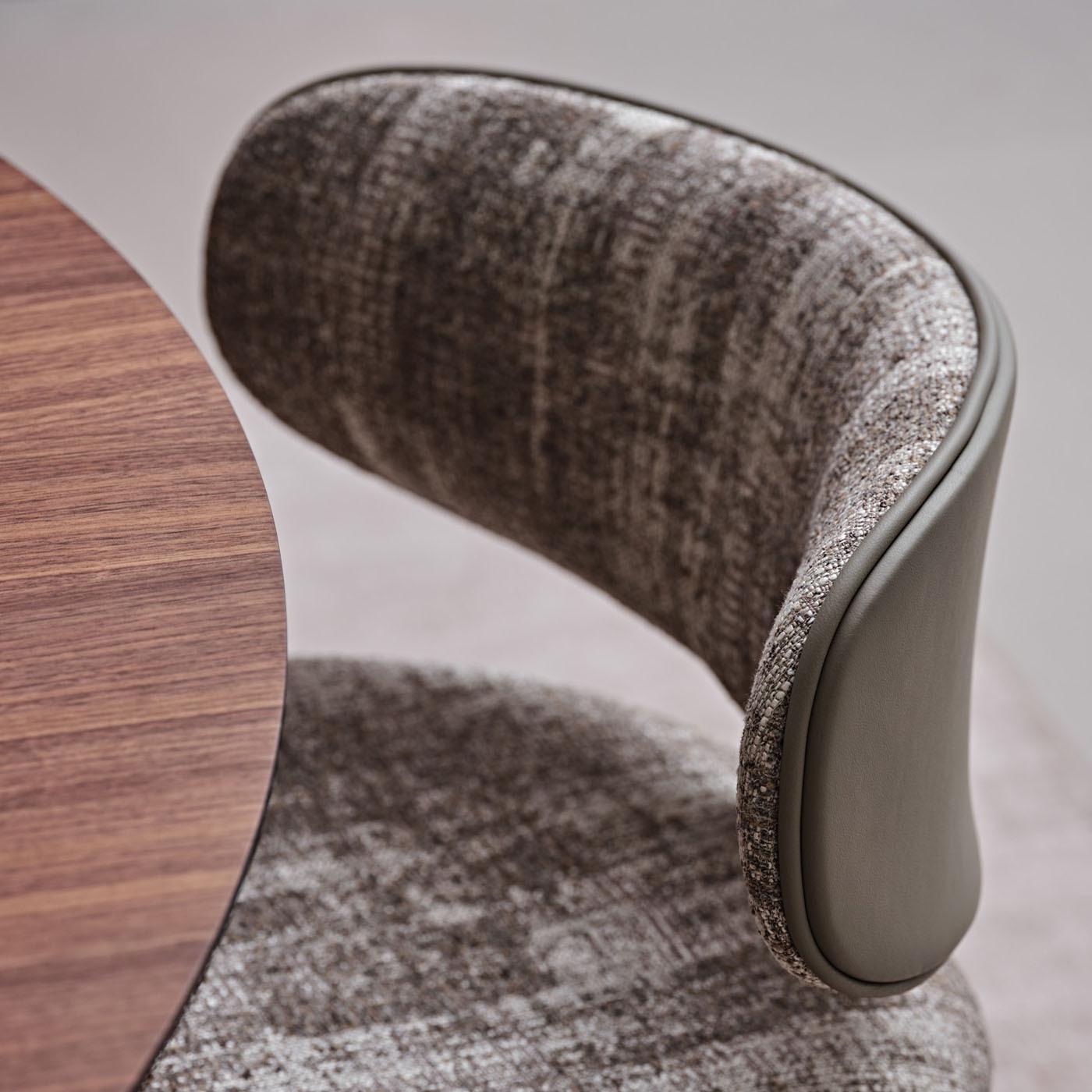 Reinterpreting the look of office designs in a refined sartorial key, this chair will impeccably complement modern decor. The cylindrical metal frame is lacquered in the same mud tone as the leather details accenting the curved beech backrest's back
