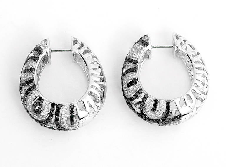 These swirl hoop earrings are made of 14k white gold featuring 1.86 ct of black and white diamonds. They are apx. 1-inch in length and weigh 8.3 grams.  These earrings can be dressed up or down.