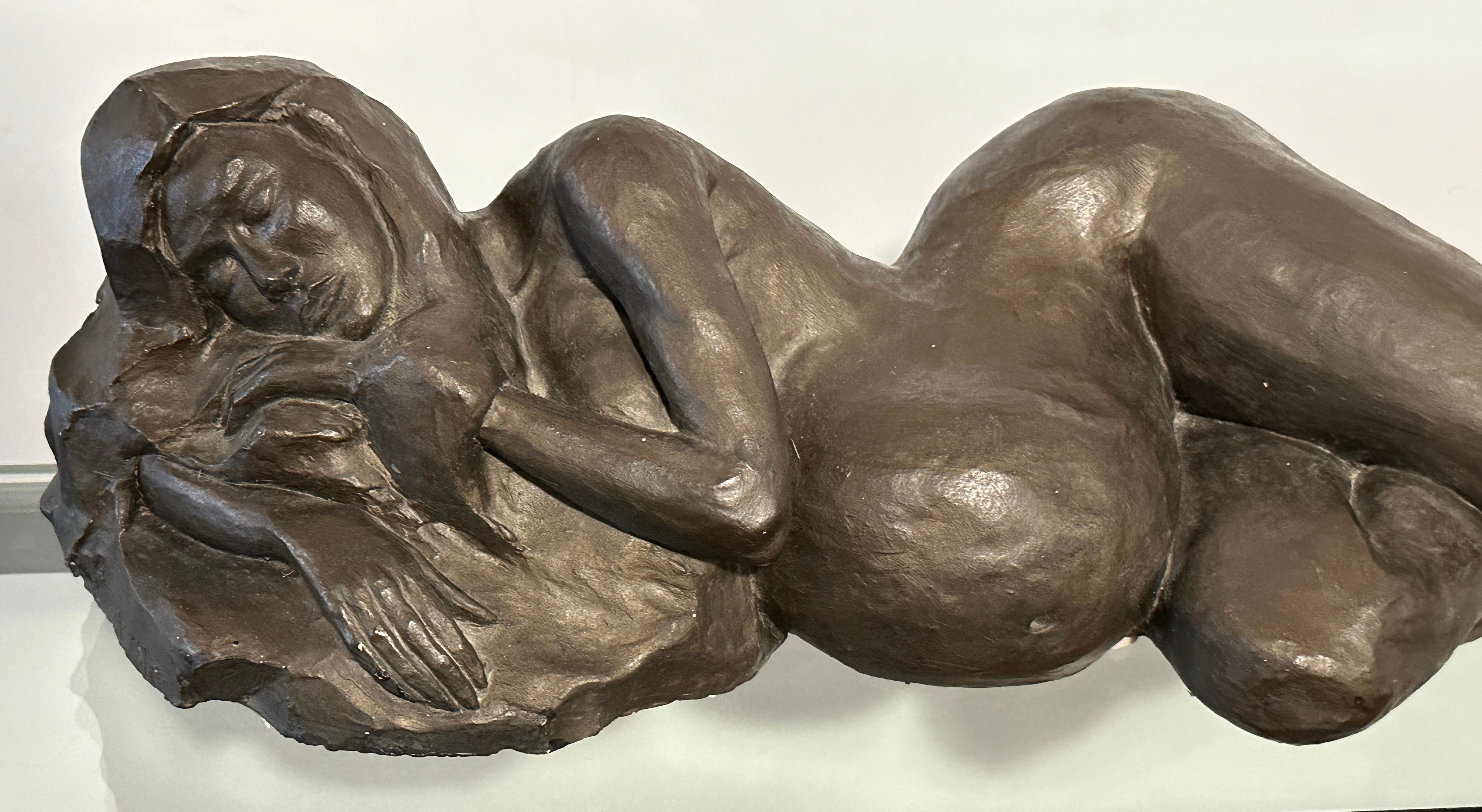 This sculpture by Natalie Krol is made of plaster with a beautiful bronze color finish. It is the cast for the bronze.
It shows a nude, pregnant woman resting. The expression on her face could almost suggest that the artist had surprised her model