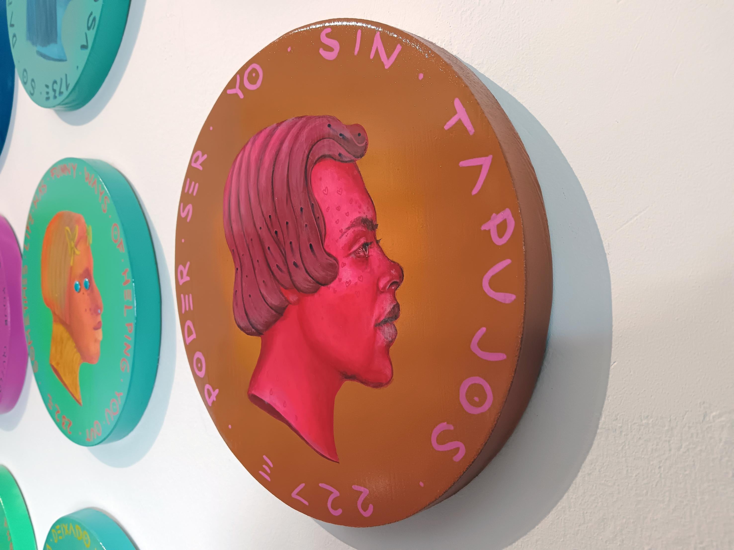 Questo ritratto circolare di Natasha Lelenco appartiene alla serie Currencies ed è incentrato sui temi dell'identità di genere, della migrazione e della resilienza queer. Realizzato in suggestivi toni cremisi su uno sfondo marrone ramato, il profilo