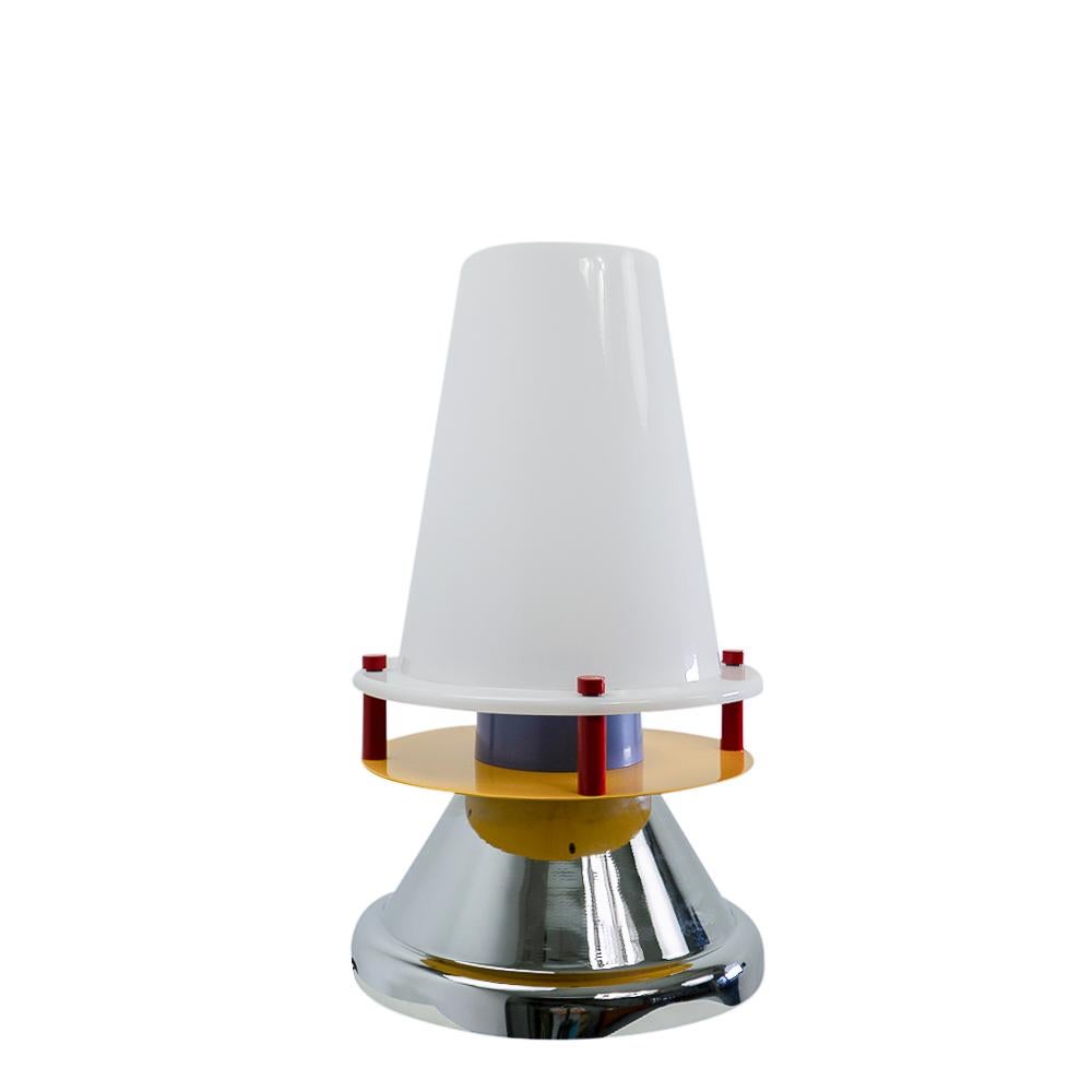 Colorful “Bordeaux” table lamp by Nathalie du Pasquier designed for Memphis-Milano during the 1980s.

This rare table lamp has an acrylic lampshade on a metal base. It is built up on a chrome underside with colorful metal elements that support the