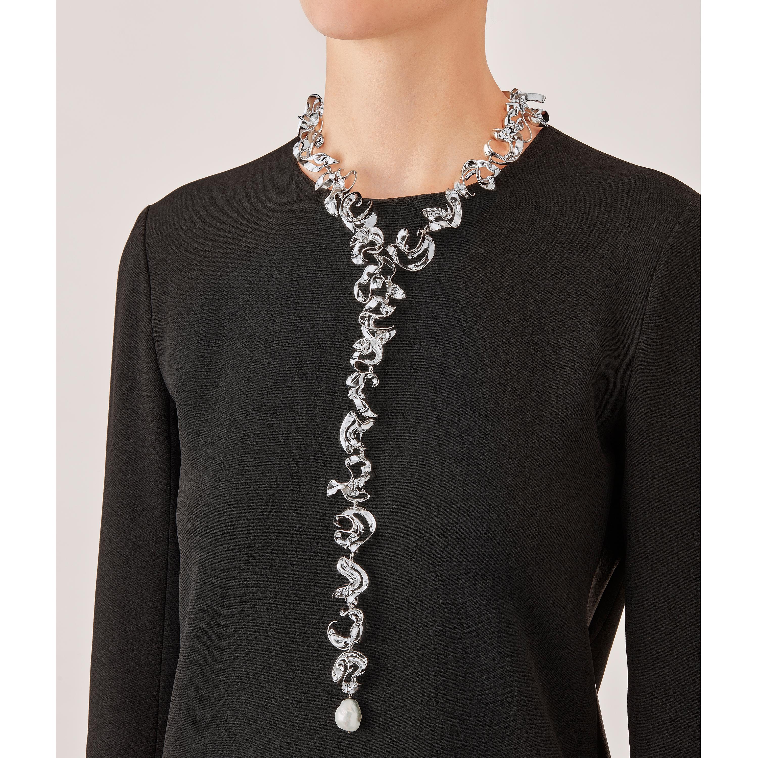 With their delicate, curved, free-form surfaces, the twenty four elements of this contemporary sculpture necklace fold and unfold with harmony and grace like glittering shell fragments or polished metalized leaves. Discretly linked to each other