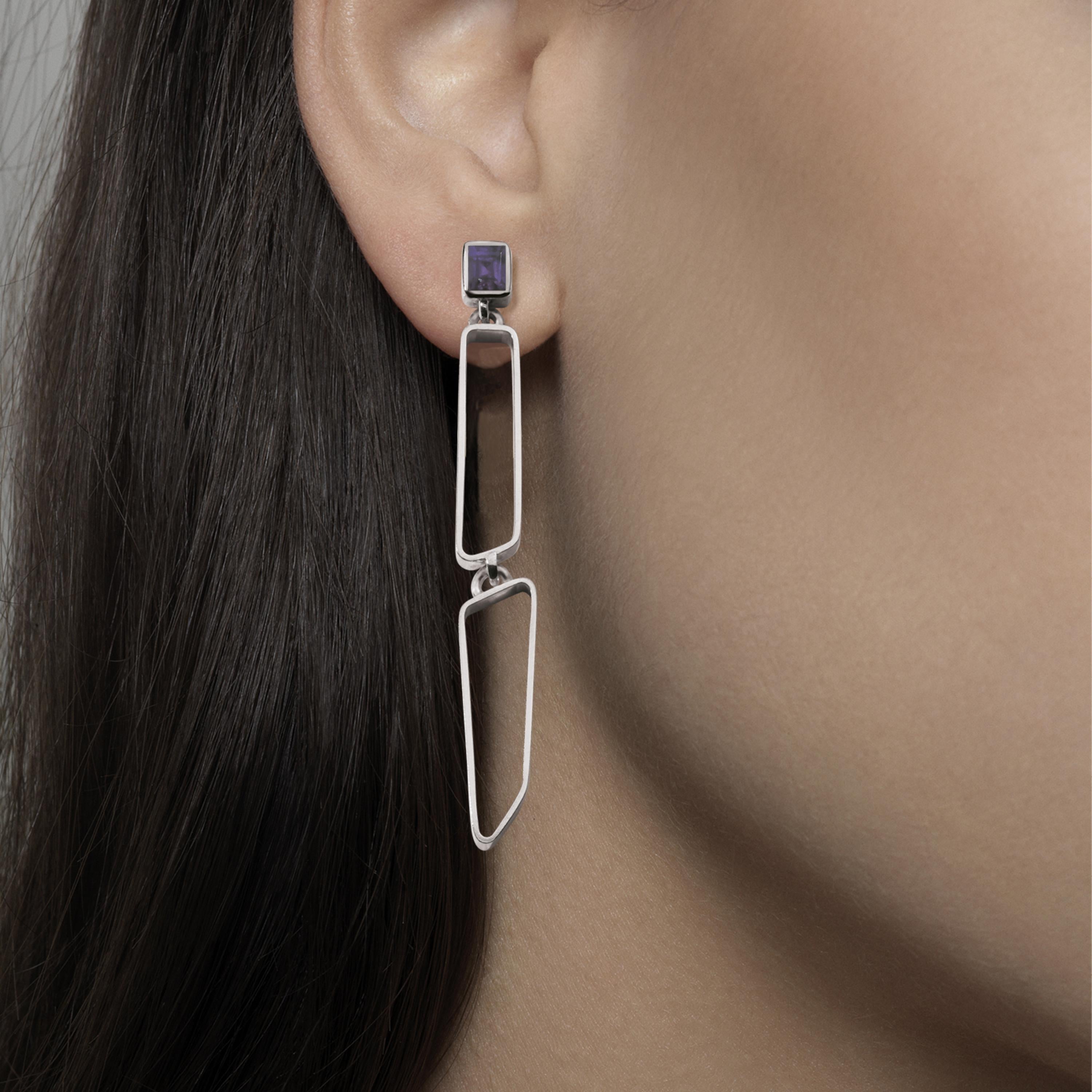 Made by hand in Nathalie Jean's Milan atelier in limited edition, the Saphir Infini Double drop dangle Earrings are in iolite and sterling silver ribbon shapes with rounded edges. The angular configurations of the sapphire’s crystalline structure